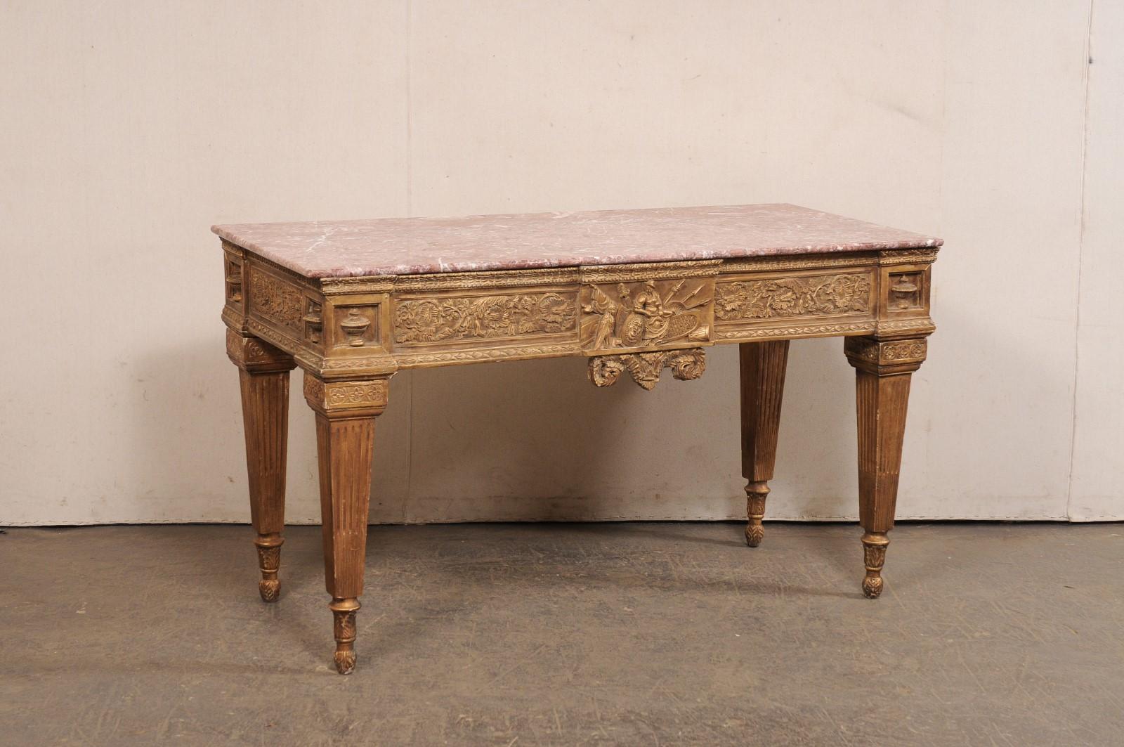 An Italian carved-wood table with marble top and robust legs. This vintage table from Italy features a rectangular-shaped marble top which rests upon an elaborately hand-carved apron with urn accents profiled at each corner, nicely trimmed