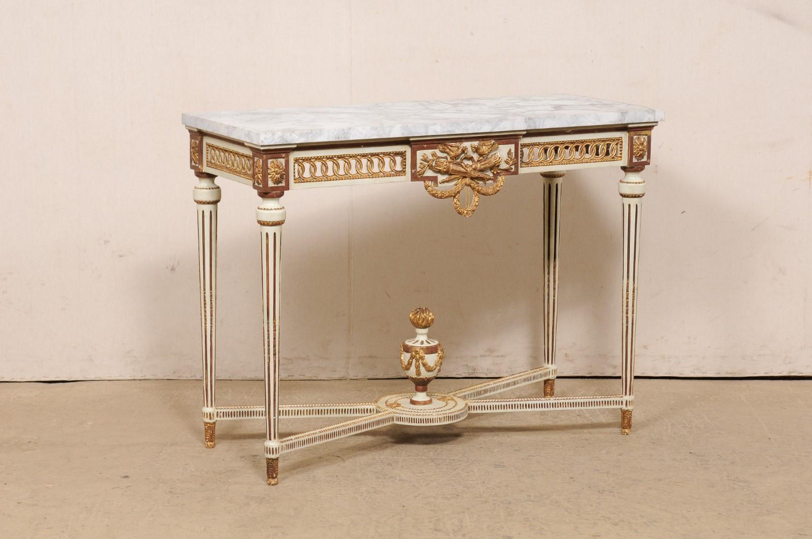 An Italian marble top console table, with urn finial accent at underside, from the Mid-20th Century (circa 1930s-1950s). This vintage table from Italy features a rectangular shaped marble top, which rests upon an exquisitely pierce-carved apron in a