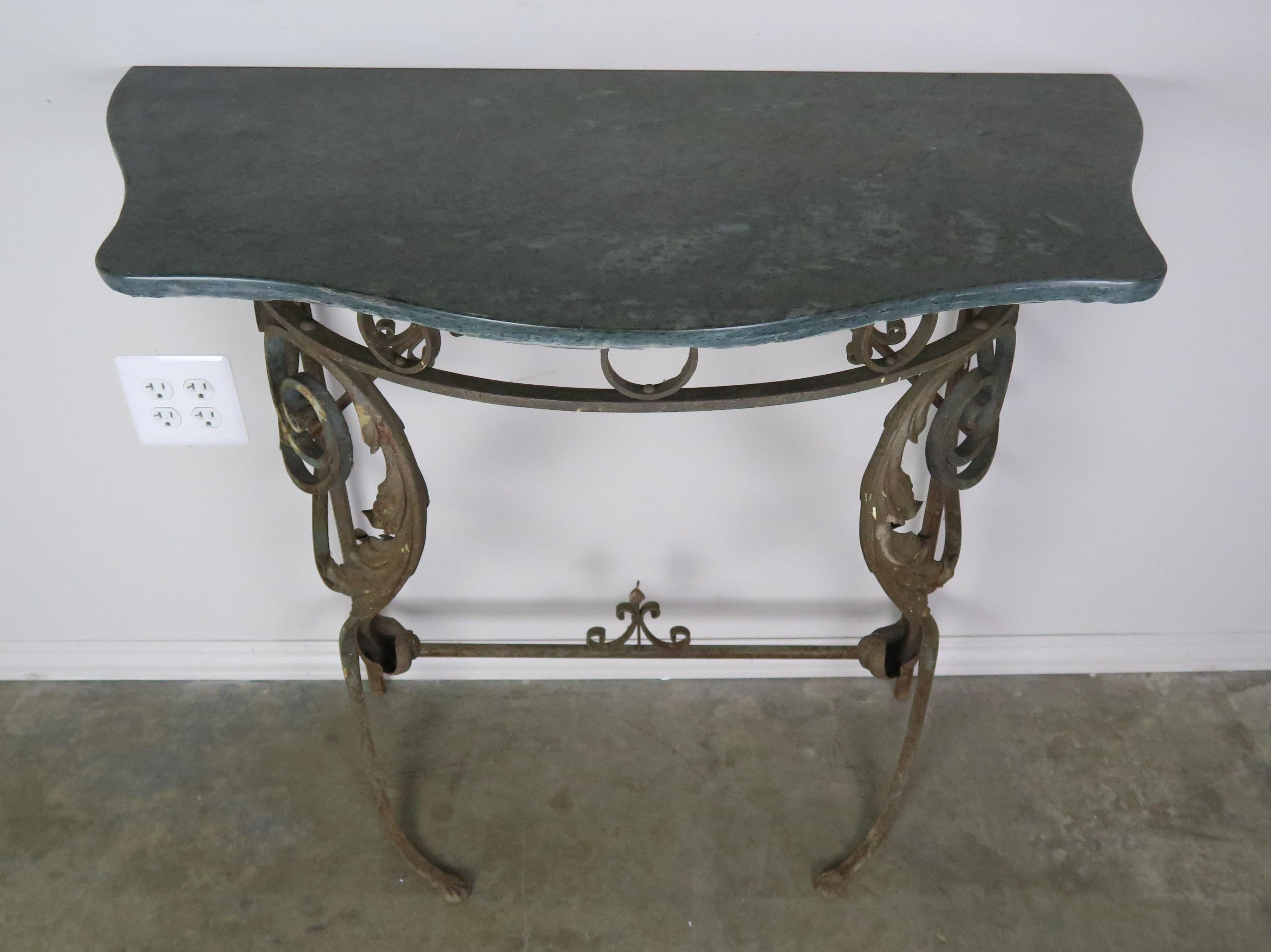 Italian marble-top iron console with gold leaf accents. Two scrolled acanthus leaves can be seen in the front with an antiqued gold leaf finish. The serpentine shaped green marble top works perfectly with the iron base.