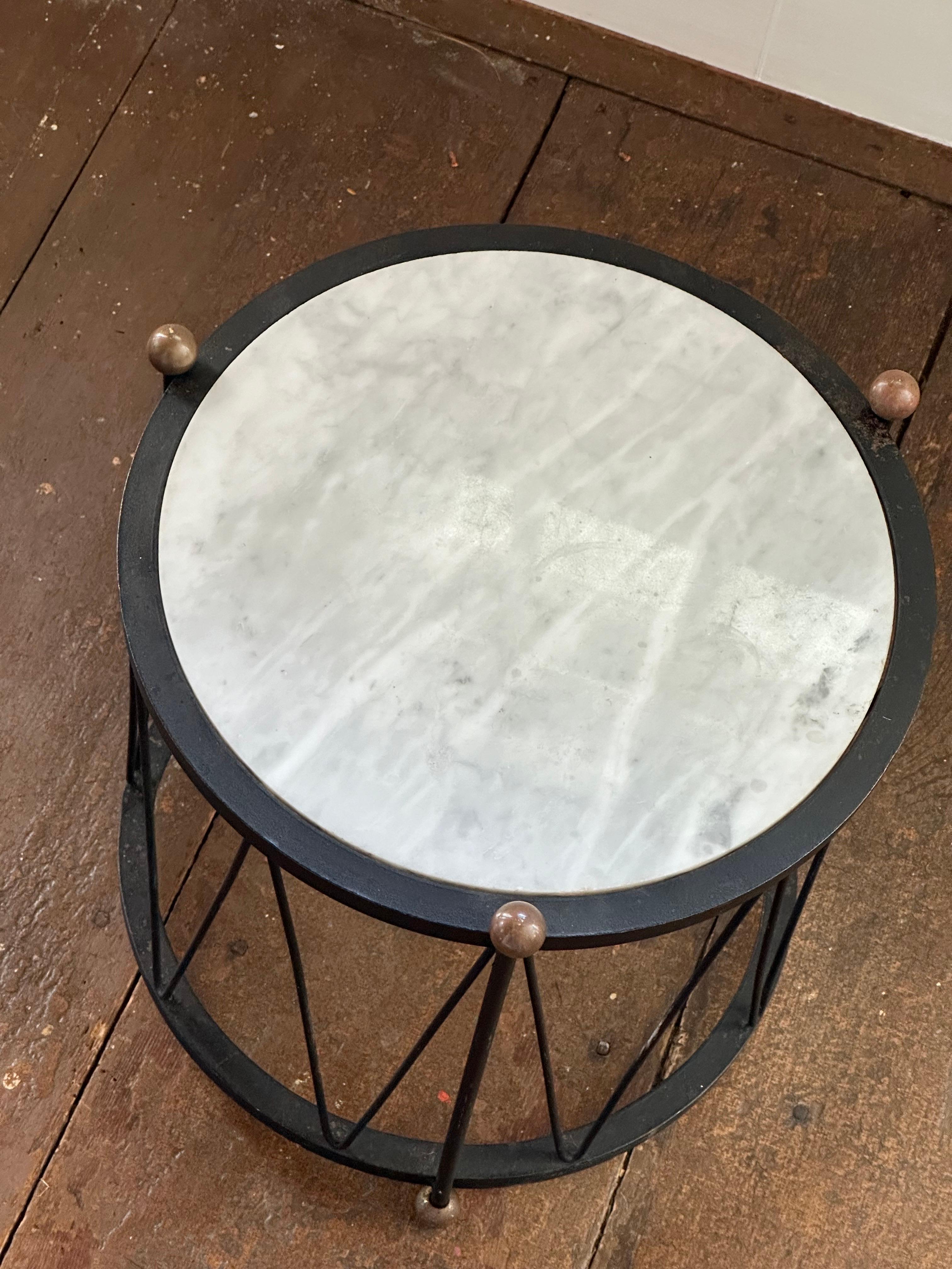 This is a mid 20th century Italian marble drum table with painted black steel base and brass ball feet and finials.  The underside of the marble top is marked 