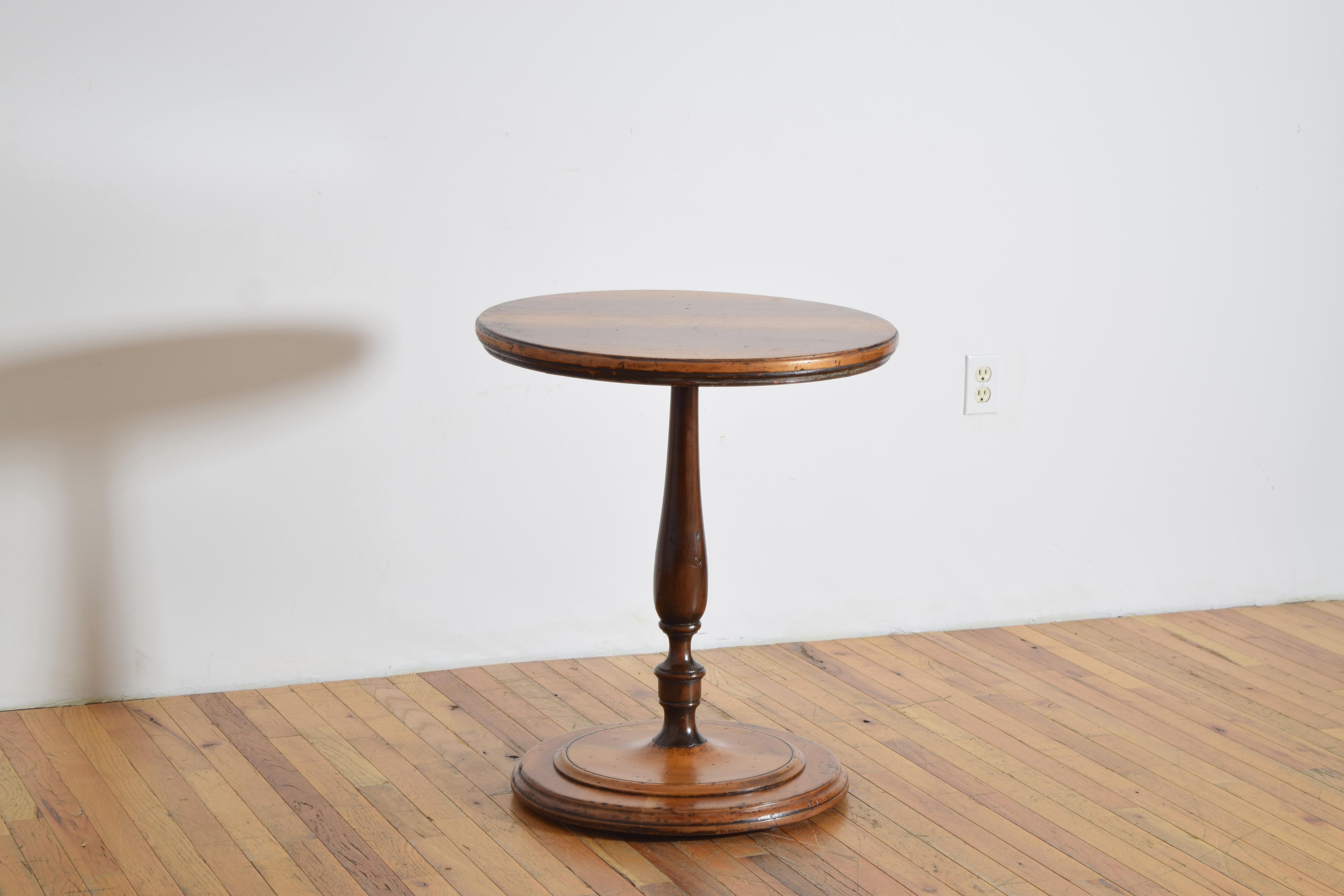 having a circular top raised on a darker walnut turned standard, the base also circular and turned to two levels, the base raised on small disk feet