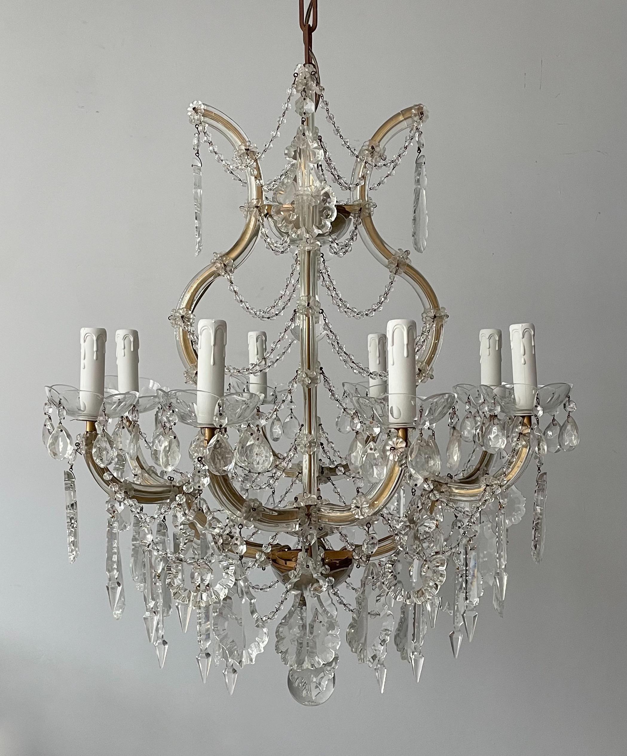 Graceful, vintage Italian crystal chandelier in the Maria Theresa style.

The chandelier consists of a gilded iron frame sandwiched between clear blown glass plates which are held in place by glass florets. French crystal pendants and garlands of