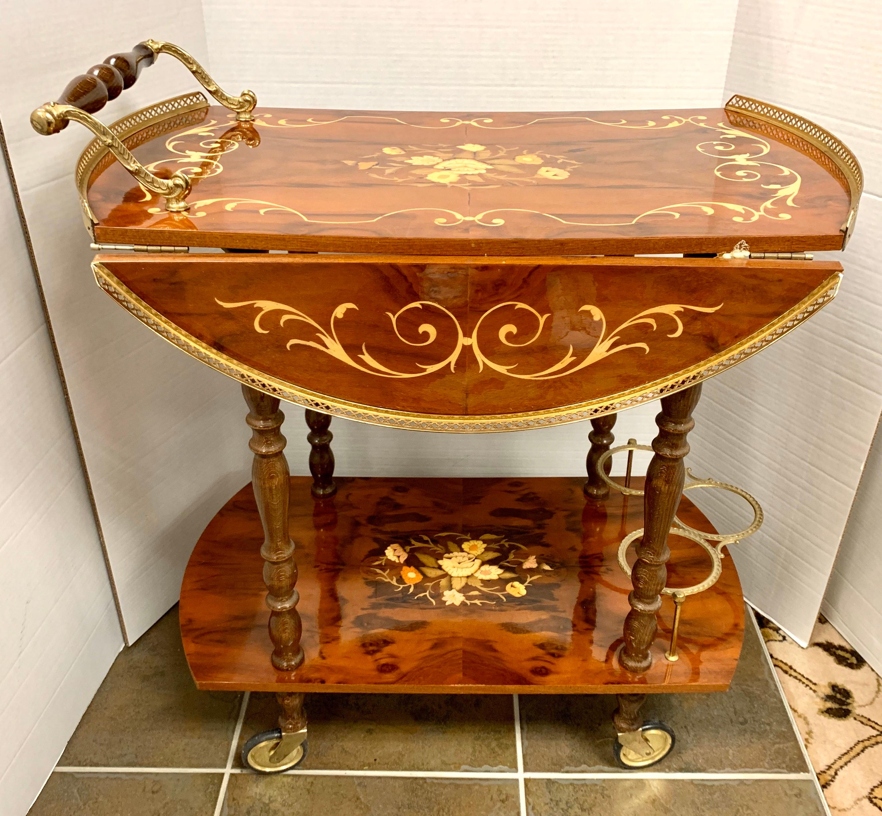 Elaborate Italian tea cart features floral marquetry of rosewood, satinwood, and tulip wood with a brass gallery top. Drop leaf sides open to a round top. Wheels are brass and roll smoothly. Fully extended, the bar cart becomes 26