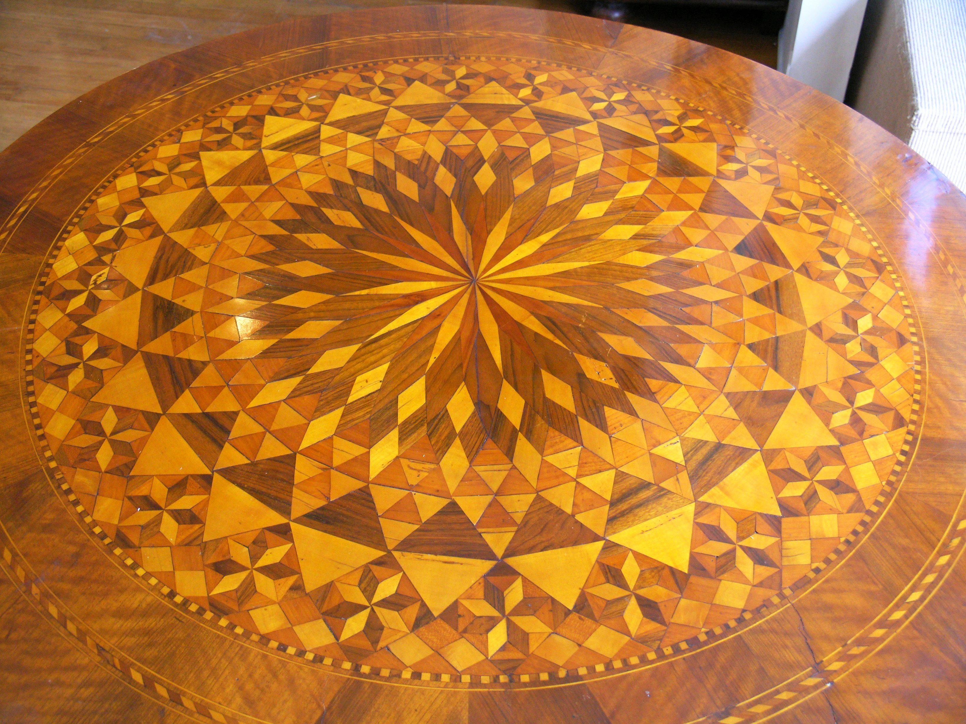 Circular marquetry inlaid top raised on a fluted standard resting on a tripartite base with slightly under scrolled feet.