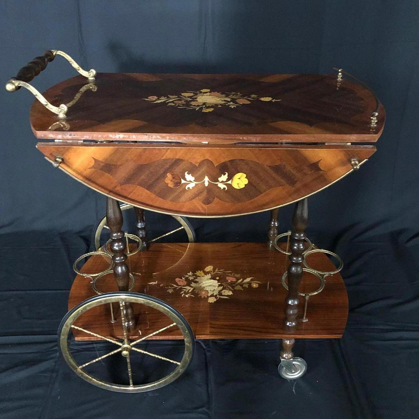 Beautiful early 20th century Italian bar cart with beautiful intricate marquetry throughout. Cart has two drop leaves for versatility and six intricate decorative brass bottle holder rings. This Italian bijou drinks trolley comprises of two levels