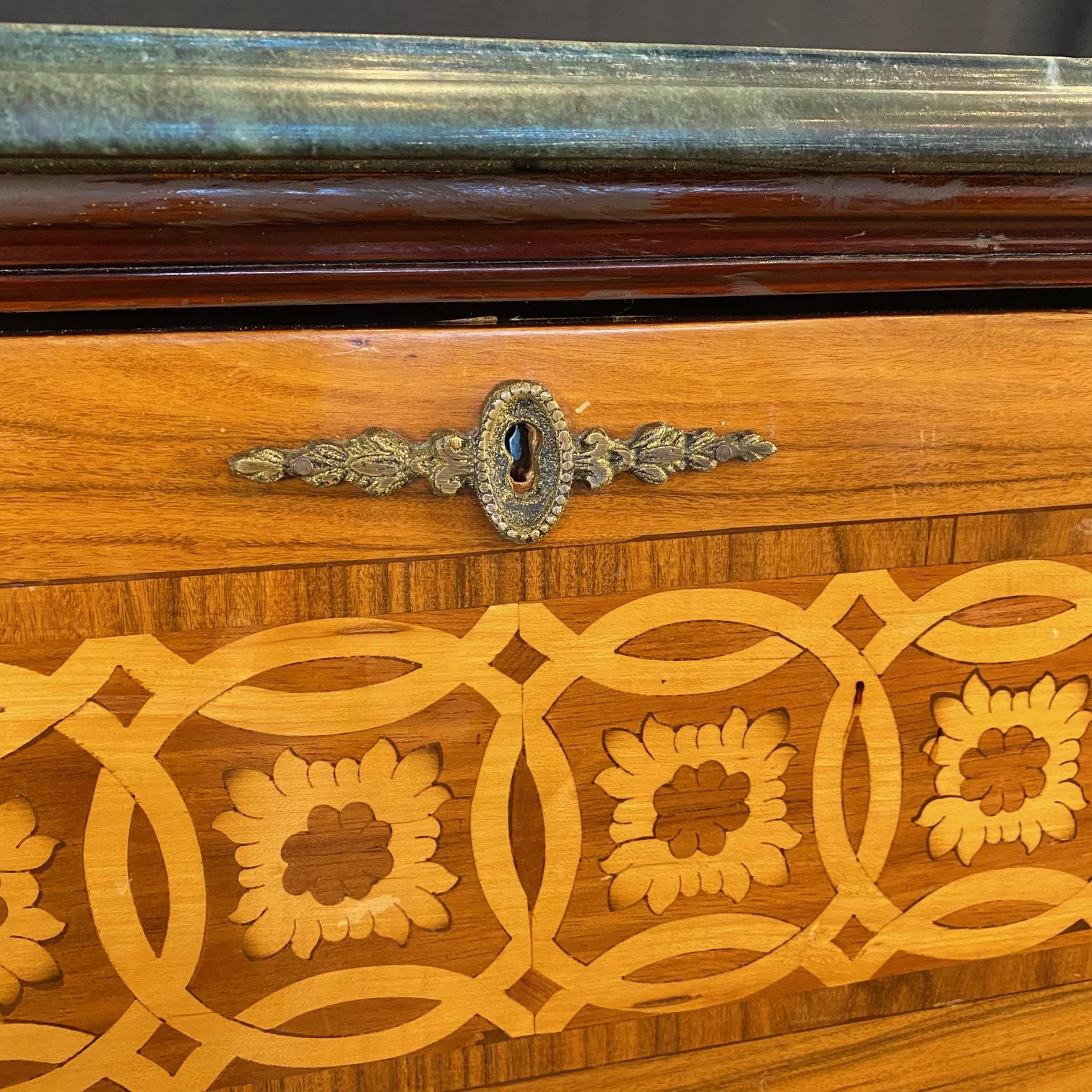 Finemente dettagliata con squisiti intarsi, questa segreteria commode italiana presenta un bellissimo piano in marmo grigio-verde e una scrivania a ribalta dietro un finto cassetto, che rivela un interno in legno di radica con una superficie di