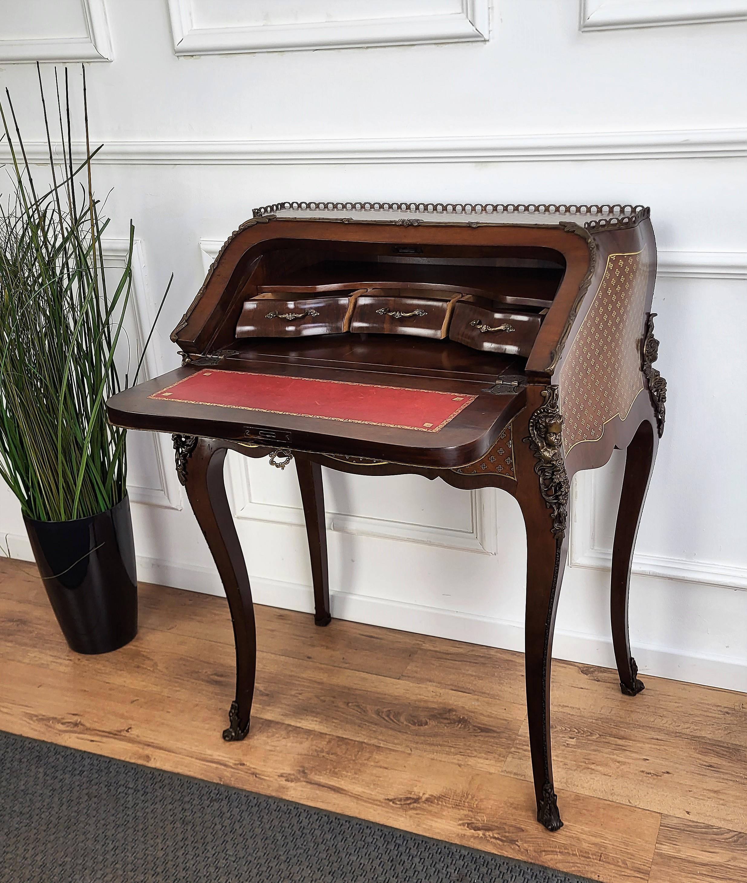 Very elegant Italian desk, writing table, with slant drop front, with the beautiful light and dark wood inlay decors in classic figures all around the piece and the amazing bronze sculptures on the legs. When opened we find the writing area in red