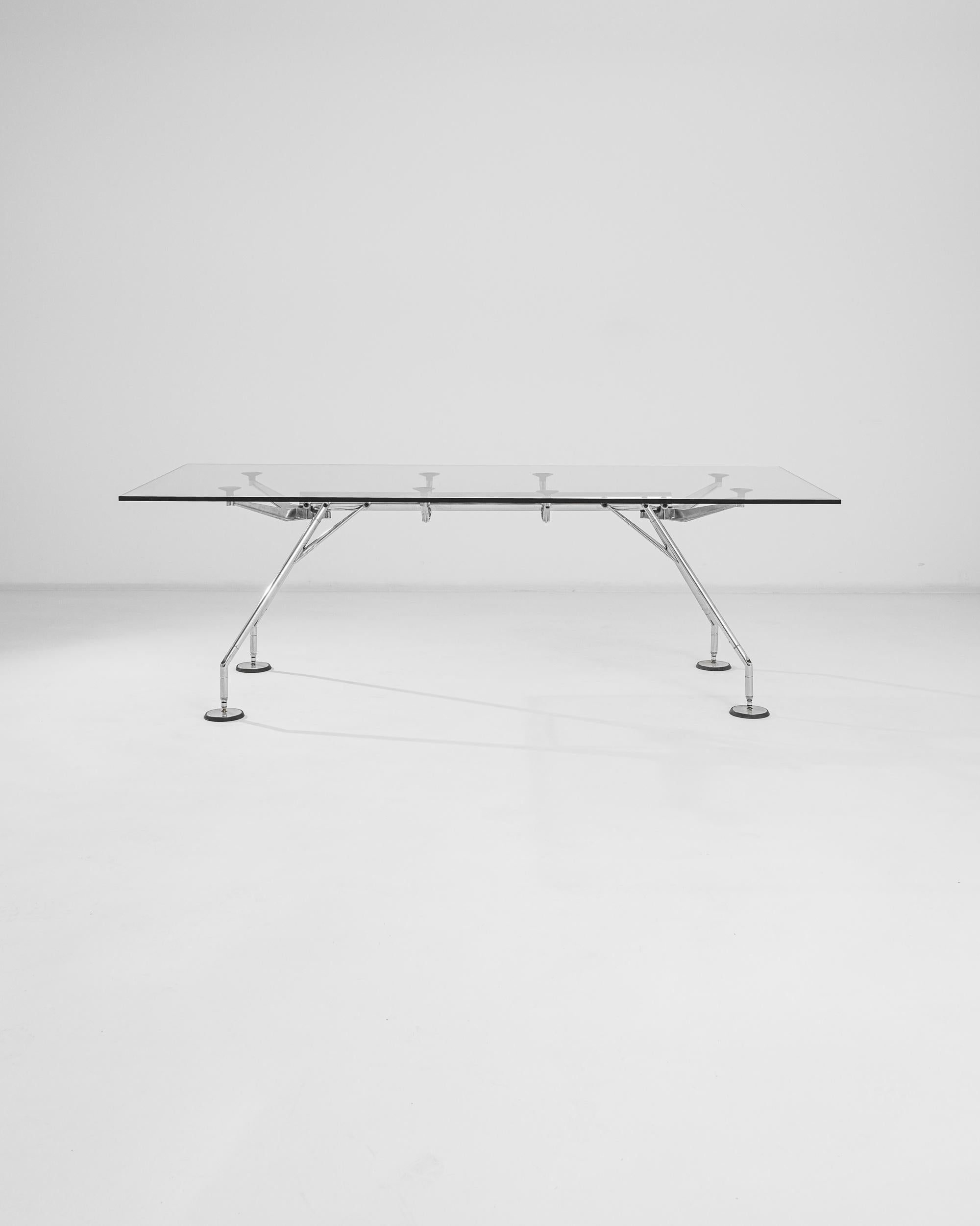 Made in Italy, this metal and glass table was imagined by designer and architect, Norman Foster, a premiere force in high-tech design. A network of metal appendages, capped with circular ends supports a thick glass top and sets this table sturdily