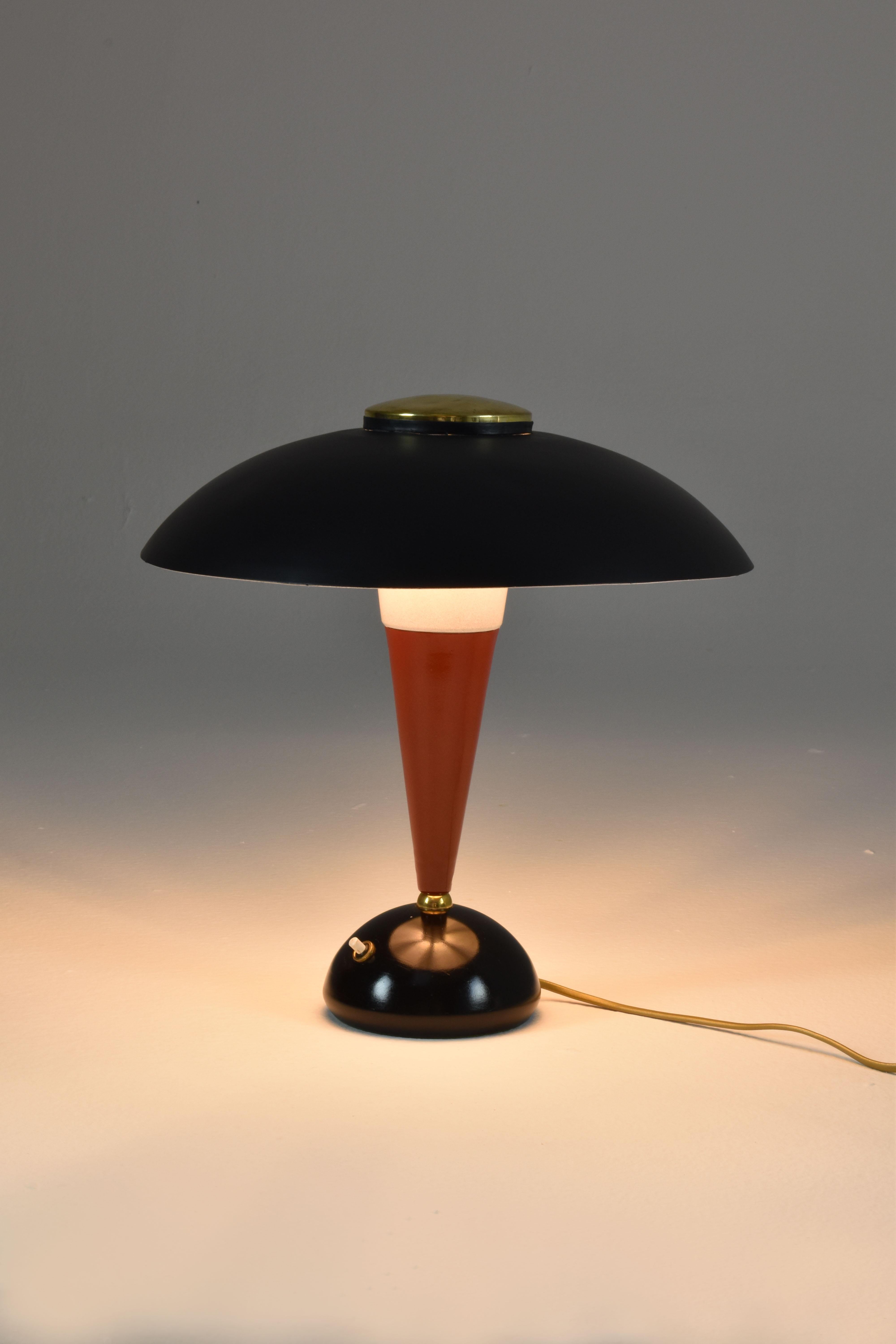 A funky  Italian 1960s table lamp designed with a black shade and base and a dark red stem. This accent light is composed of aluminium and pretty gold brass accents. 

Professionally re-wired with the highest standards and universally compatible.