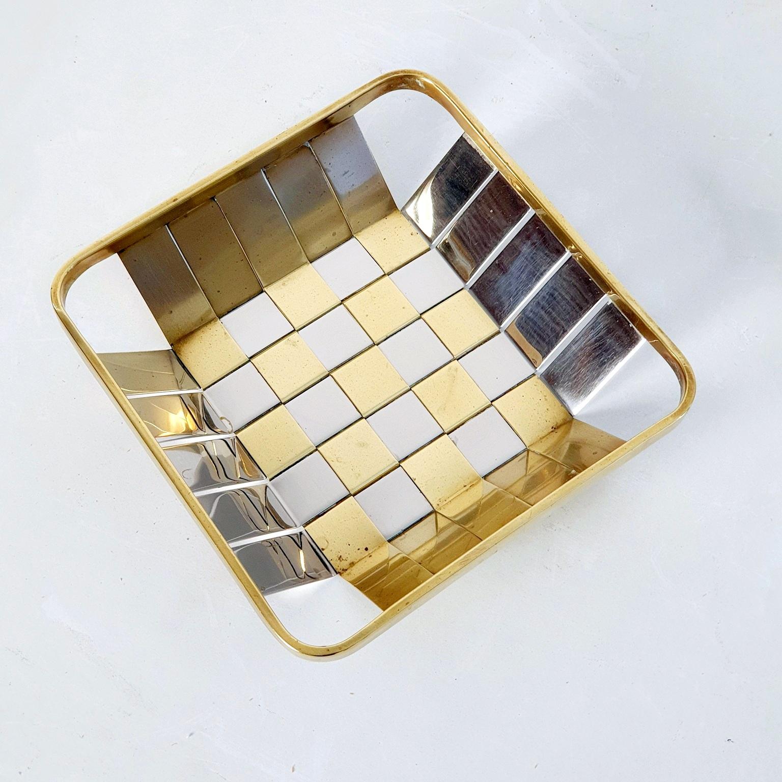 An Italian square basket in silver and gold metal made with weaving technique. This piece is typical for the style of the era evoking the designs of Willy Rizzo and Rome Rega for instance. Works great as a fruit or bread basket.