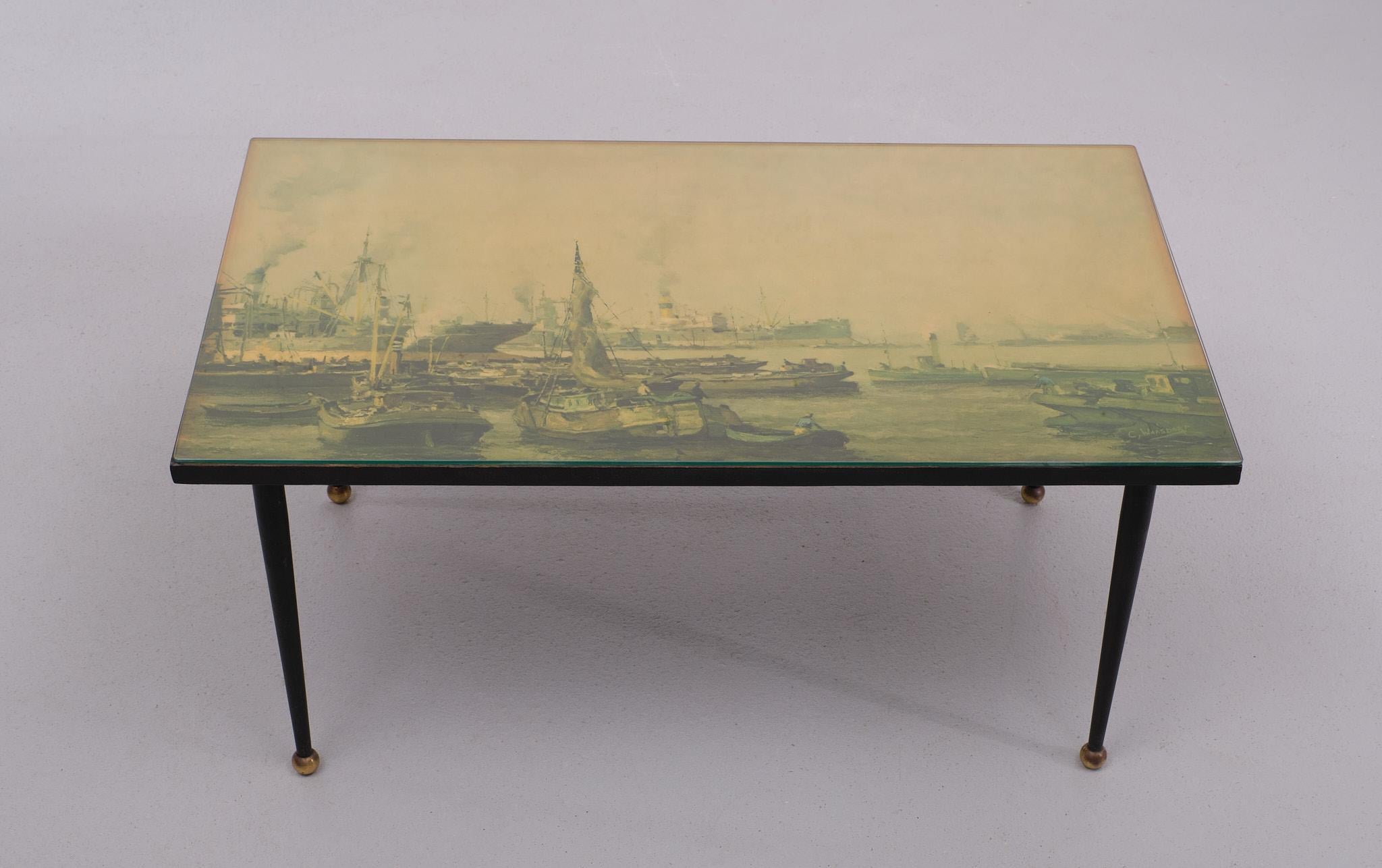 Very nice Italian coffee table . The top of the table is decorated with a nice Print 
from a  Harbor scene  from the Dutch painter C Waasdorp . Top is protected by resin.
and a Glass plate . Tapered metal legs with brass knobs . 

Please don't