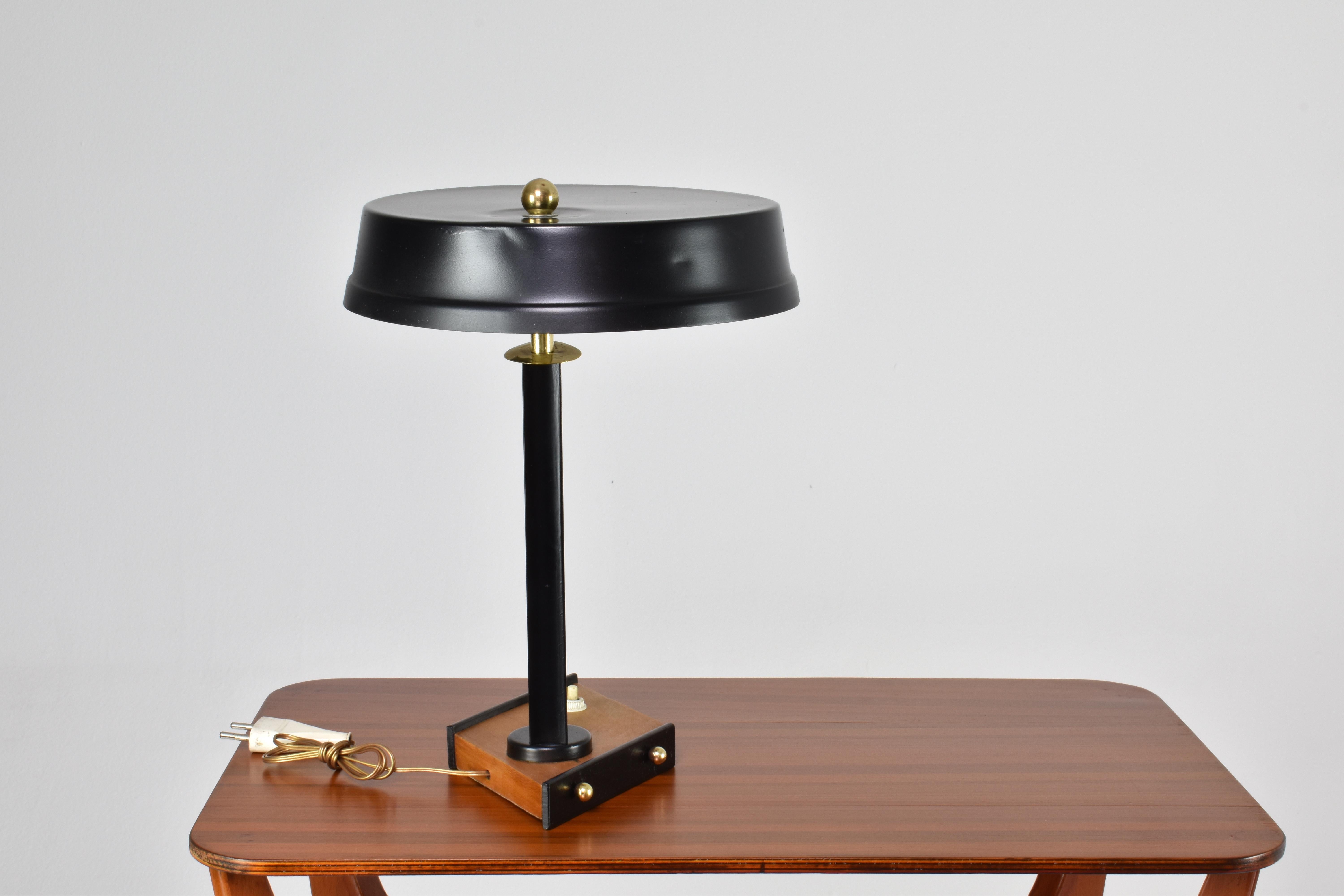 This Italian vintage desk lamp is a statement in design. This piece is meticulously restored and rewired to international standards. It features an elegant matte black lacquer finish, complemented by a wooden base, creating a contrasting aesthetic.