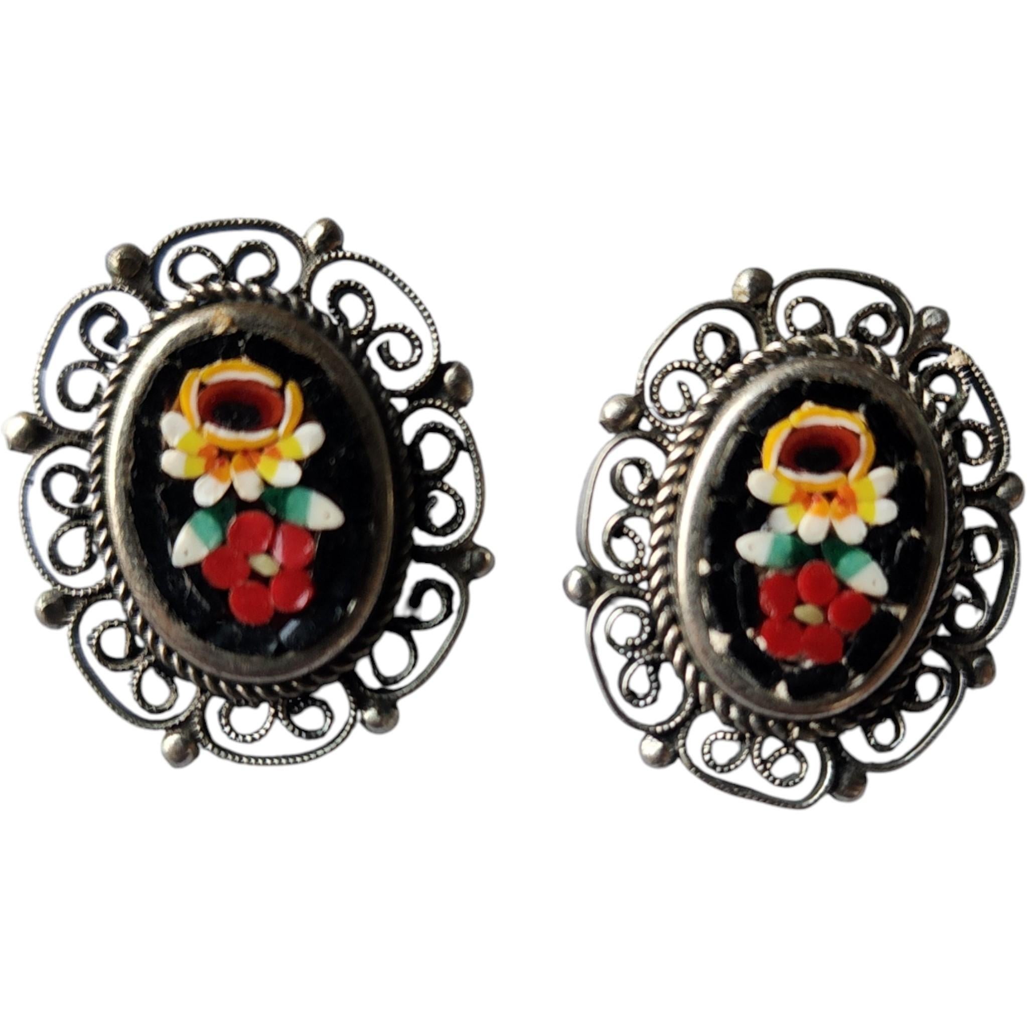 This charming Italian micro mosaic jewelry set includes a brooch and matching clip-on earrings, beautifully crafted in the 1950s. Each piece showcases intricate floral micro mosaic designs set into black glass, bordered by delicate silver-toned