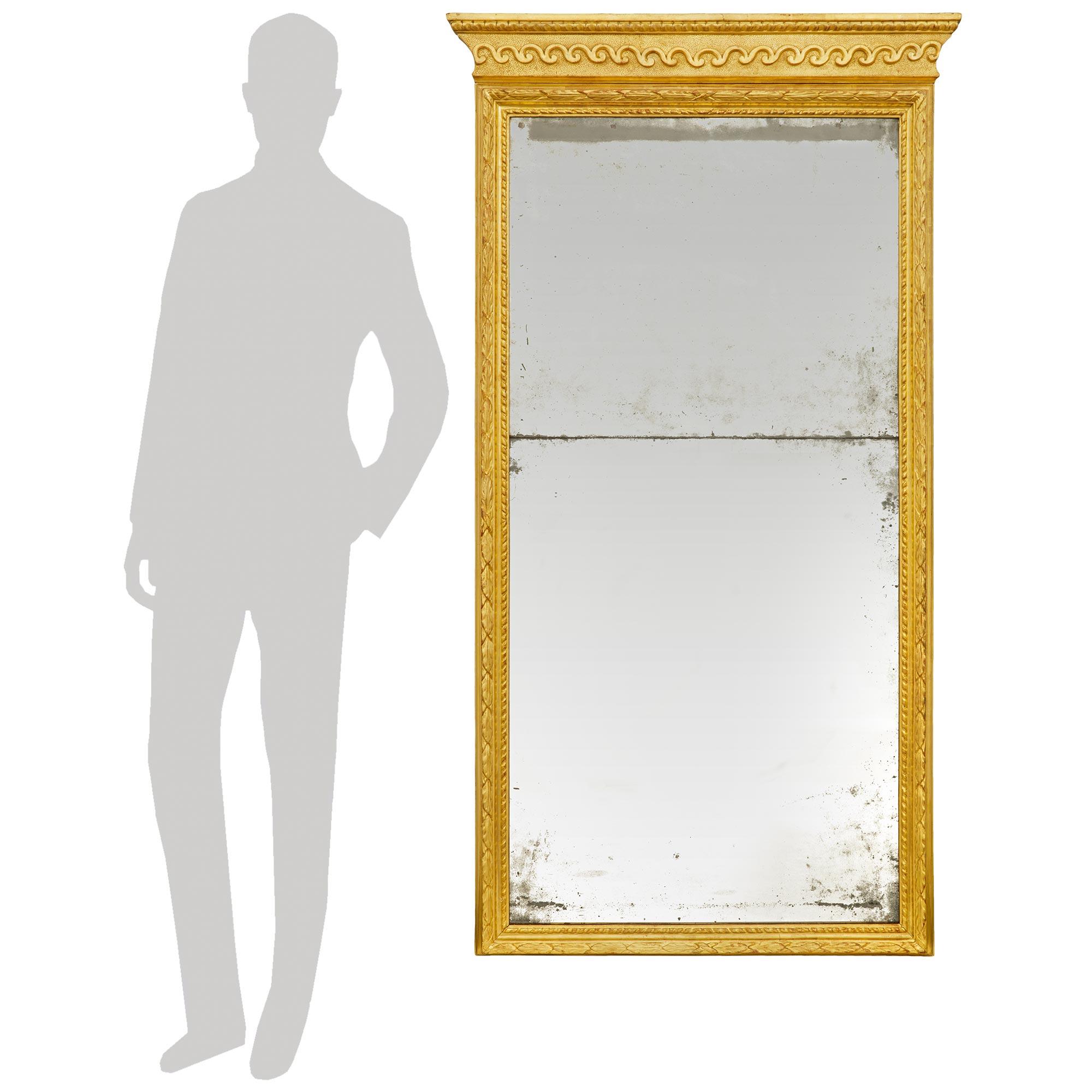 Un elegante y muy decorativo espejo italiano de madera dorada de mediados del siglo XVIII, de la época de Luis XVI. Este impresionante espejo vertical conserva todas sus placas de espejo y dorados originales. Las placas de espejo están rodeadas por