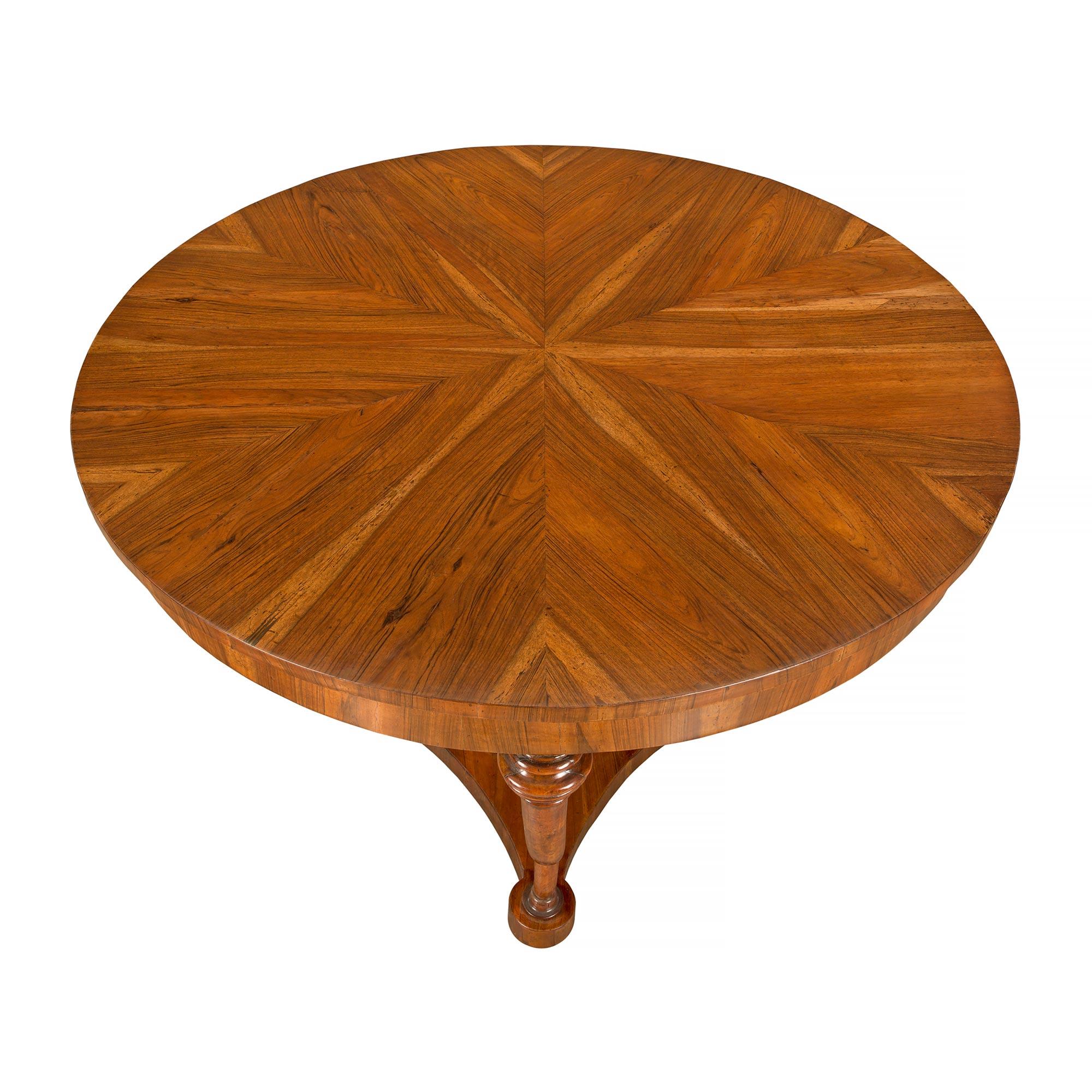 A very attractive Italian mid 18th century Tuscan walnut center table. The table is raised on a concave sided bottom tier with scrolled supports at each corner. The central fut is a solid fluted column that supports the walnut top and apron. All