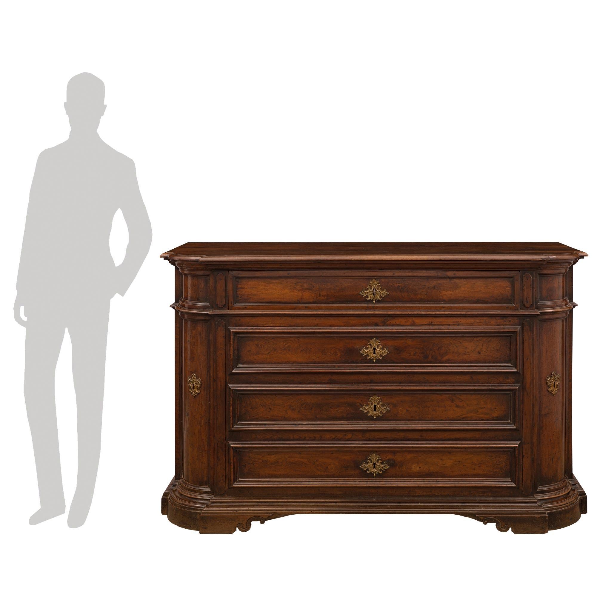 A handsome and most impressive Italian mid-18th-century walnut commode from Naples, circa 1740. The chest is raised by elegant lightly scrolled supports below an elegant mottled stepped wrap-around band at the base. At the center are four drawers,