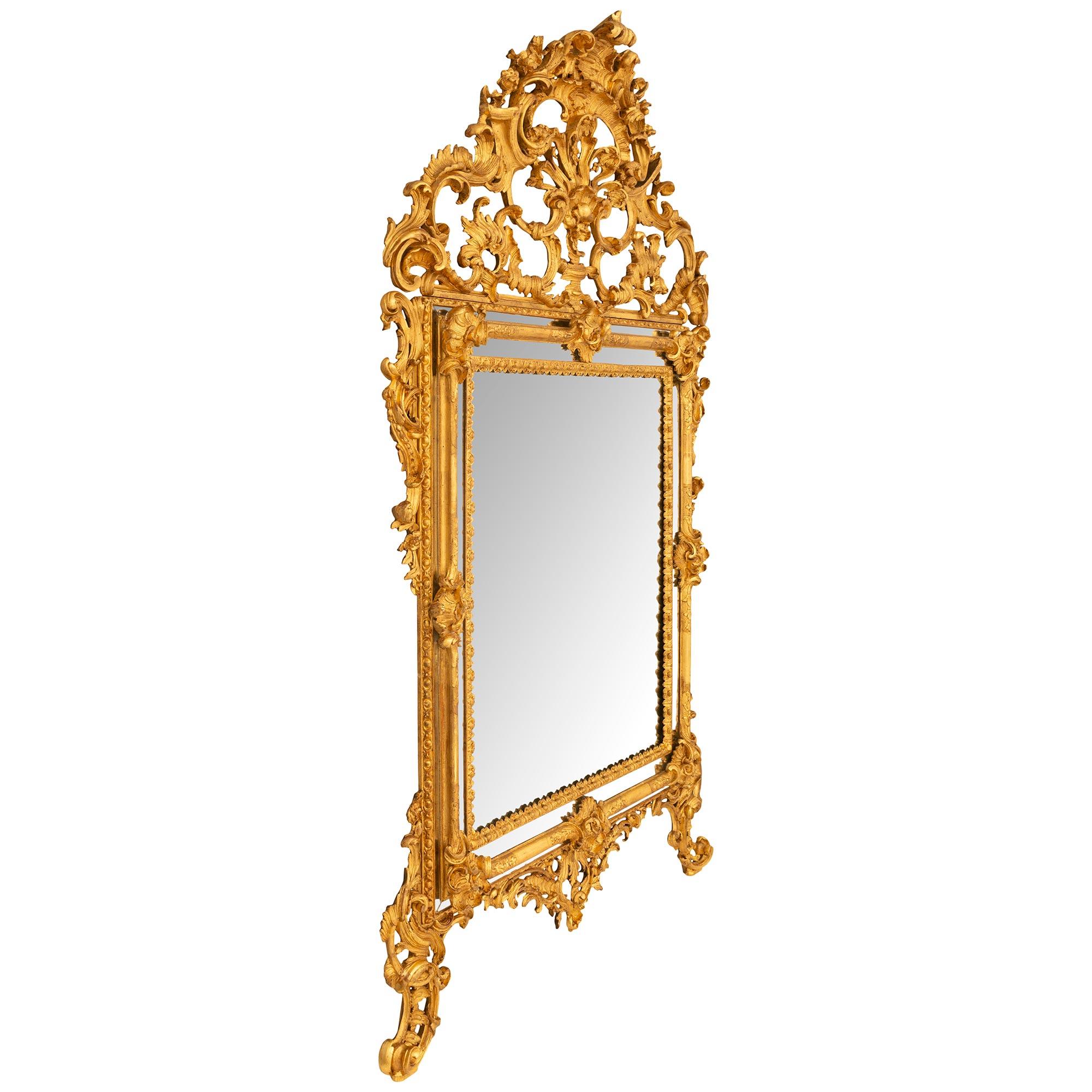 An impressive Italian mid 19th century Baroque st. triple framed giltwood mirror. The large scale mirror is raised by pierced S scrolled supports flanking the pierced central foliate reserve. The triple framed mirror is decorated by eight carved