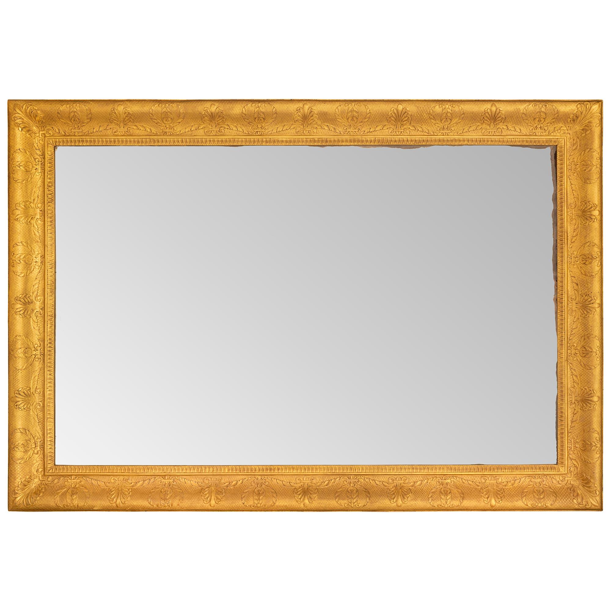 Magnifique miroir en bois doré de style néo-classique italien du milieu du 19e siècle. La plaque de miroir rectangulaire d'origine est encadrée dans un cadre en treillis en bois doré avec de jolies palmettes répétées tout au long et un bandeau