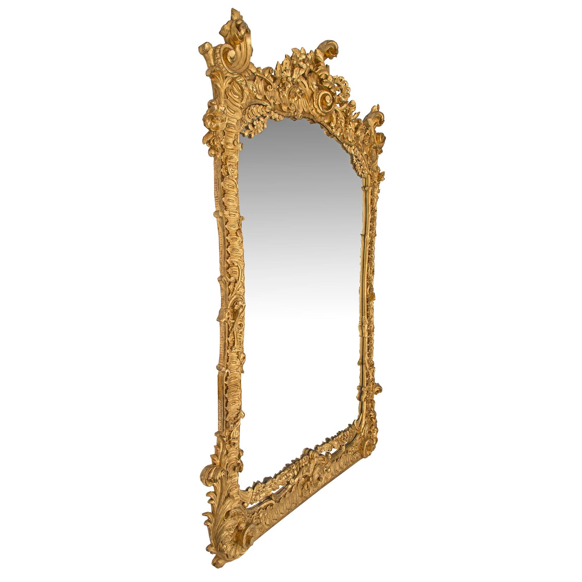 An exceptional Italian mid 19th century Rococo St. giltwood mirror. The original mirror plate is framed within an impressive and richly detailed giltwood border. Above the straight base and leading up the curvaceous sides are intricately carved