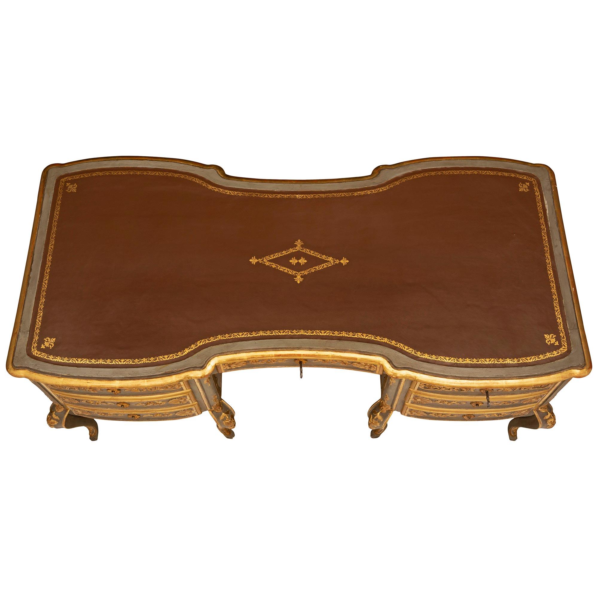 A spectacular and extremely unique Italian mid 19th century Venetian st. patinated and giltwood desk. The most decorative seven drawer desk is raised by eight elegant luxuriously curved tapered legs with finely carved giltwood acanthus leaves and