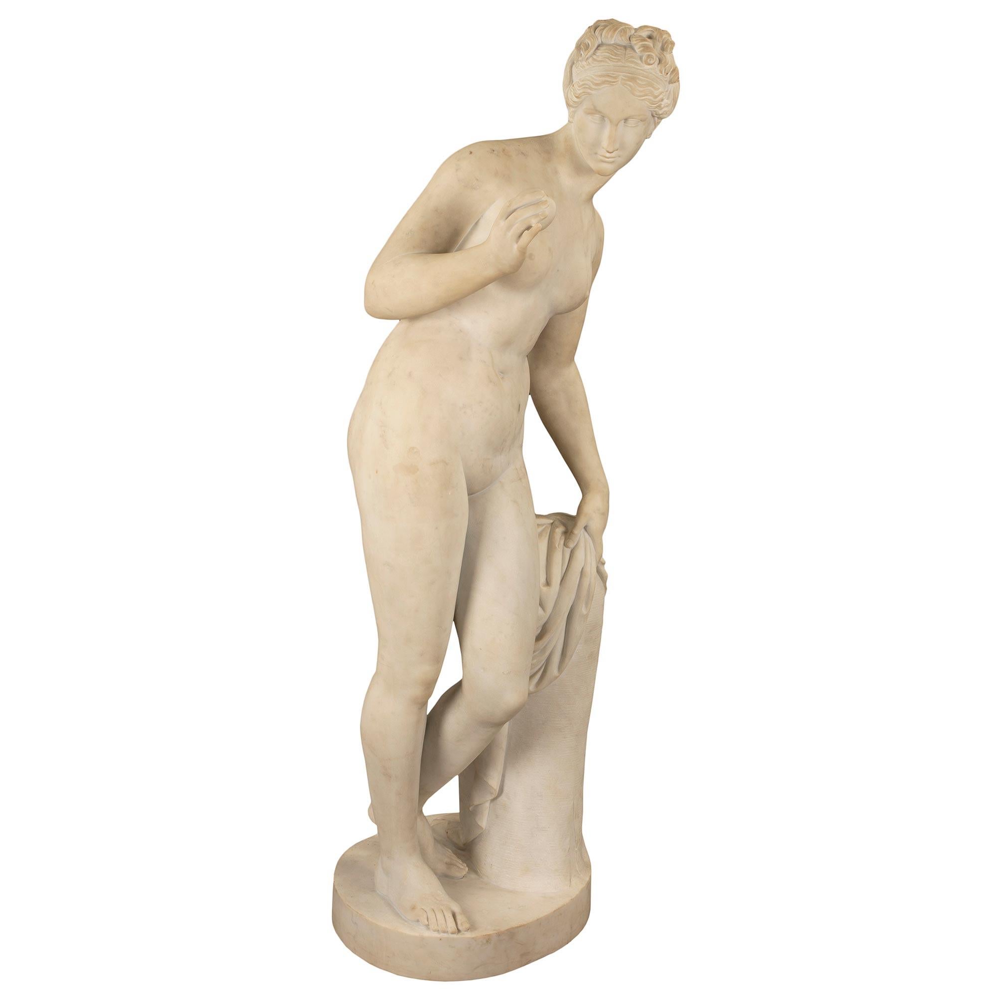 An exquisite and high quality Italian mid 19th century white Carrara marble statue of Venus. This almost life size statue, depicts the goddess leaning against a tree stump covered by a piece of cloth. She is gazing at an apple that she holds in her