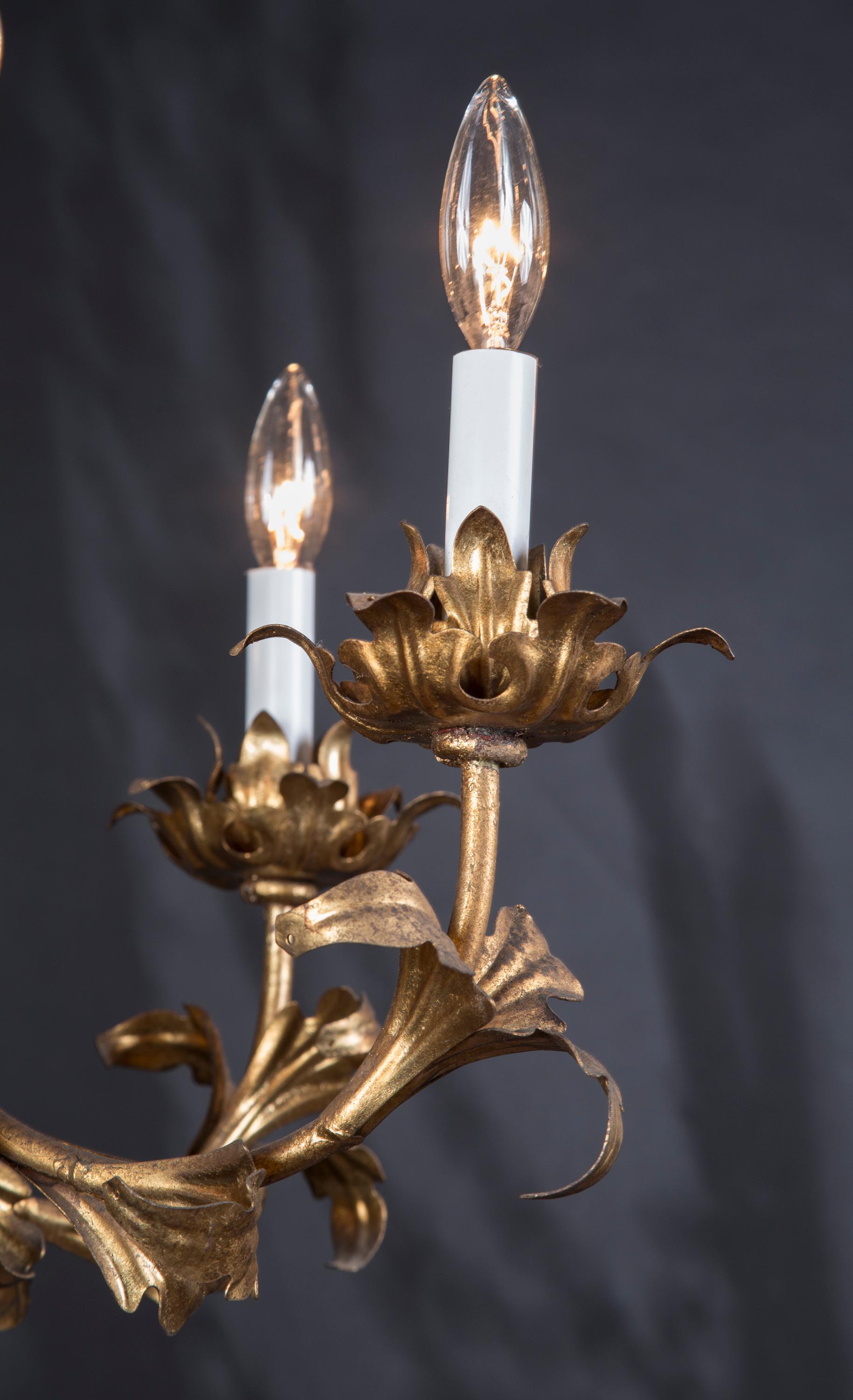 This beautiful Louis XV chandelier is made of gilded tole, gold plating on tin, and joins our collection from Italy. The piece dates back to the mid 20th Century, circa 1950, and offers a unique shape with a foliate motif throughout. Floral bobeches