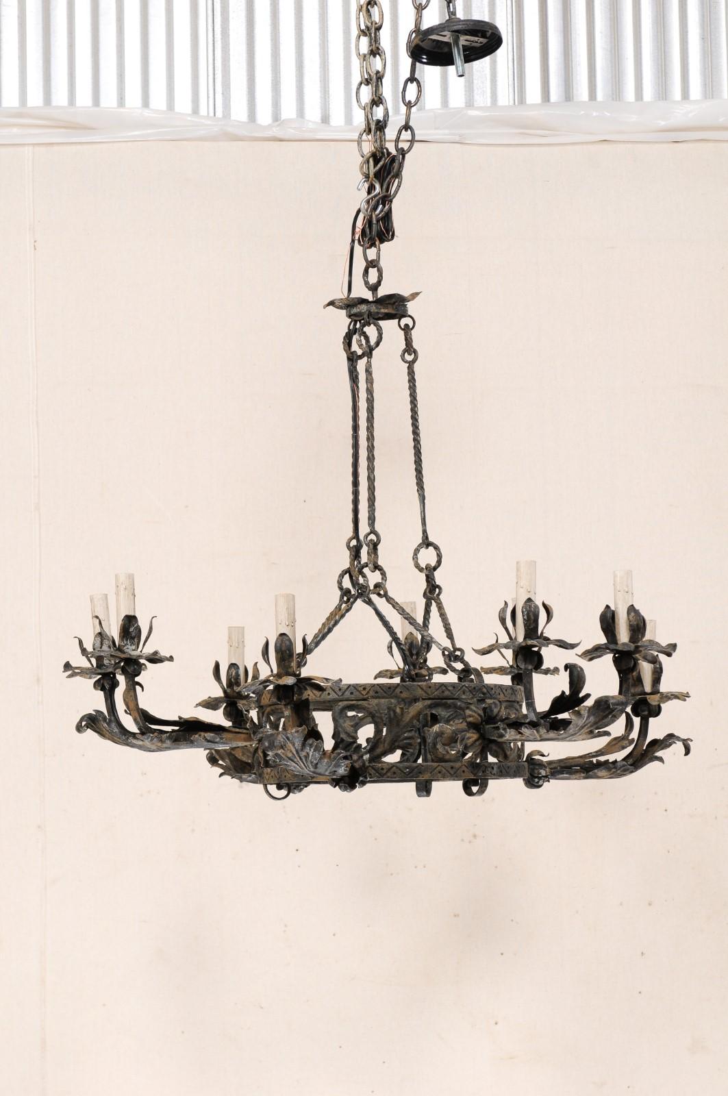 An Italian nine-light forged-iron chandelier from the mid 20th century. This vintage chandelier form Italy features a double-ringed central gallery, adorn with scrolled leaf motif and a dot and triangular design carved along the exterior of each