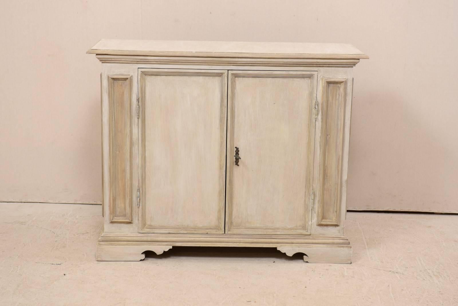 An Italian painted wood cabinet from the mid-20th century. This vintage Italian cabinet features two recessed panel doors flanked with two vertically recessed decorative panels. The recessed panel design is carried through on either cabinet side,