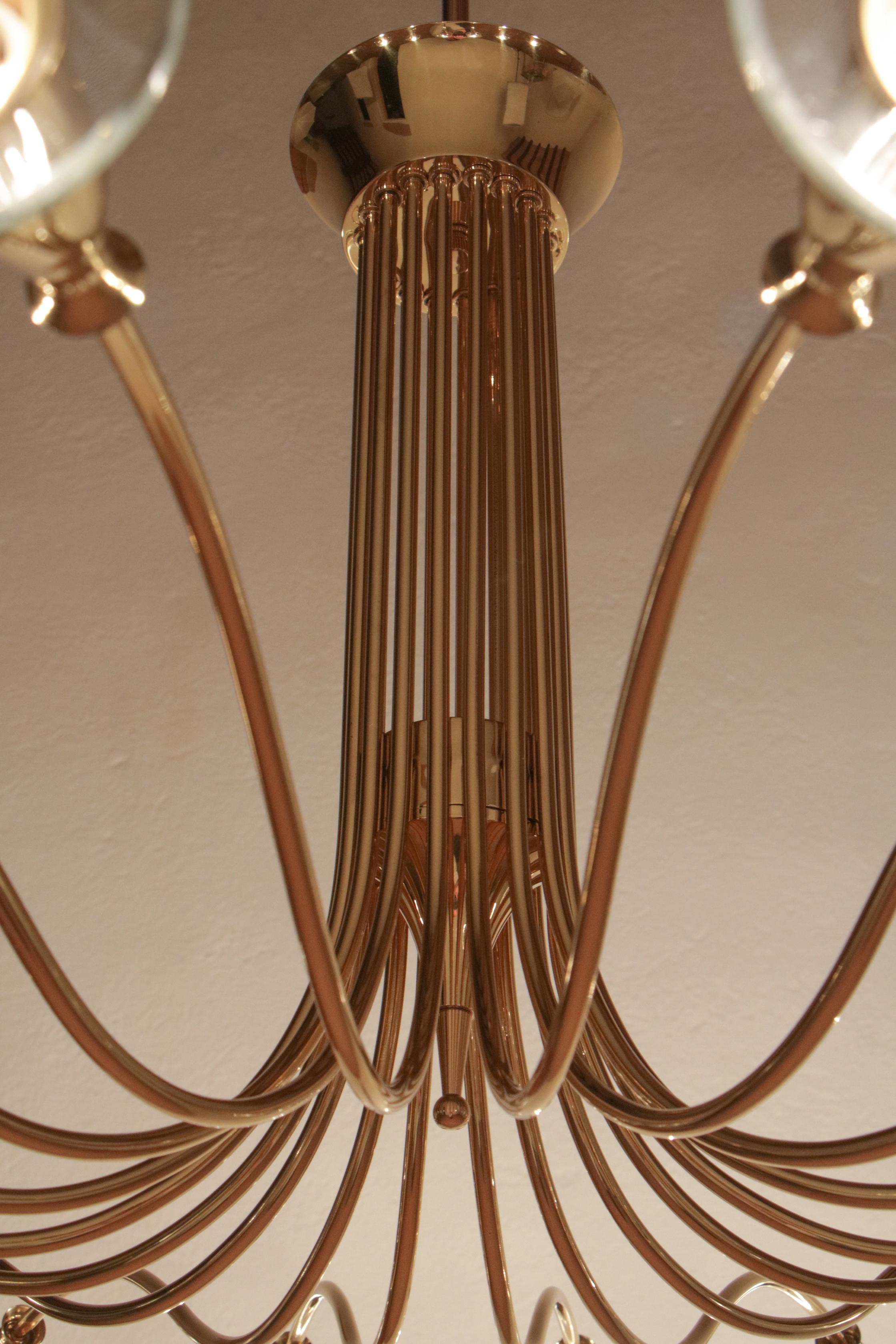 Magnifico lampadario disegnato da Angelo Lelli per Arteluce nel 1950. Realizzato in ottone lucido con vetri molati, questo lampadario presenta diciotto luci di formato E14. Il design di grande impatto scenico si unisce a una qualità esecutiva