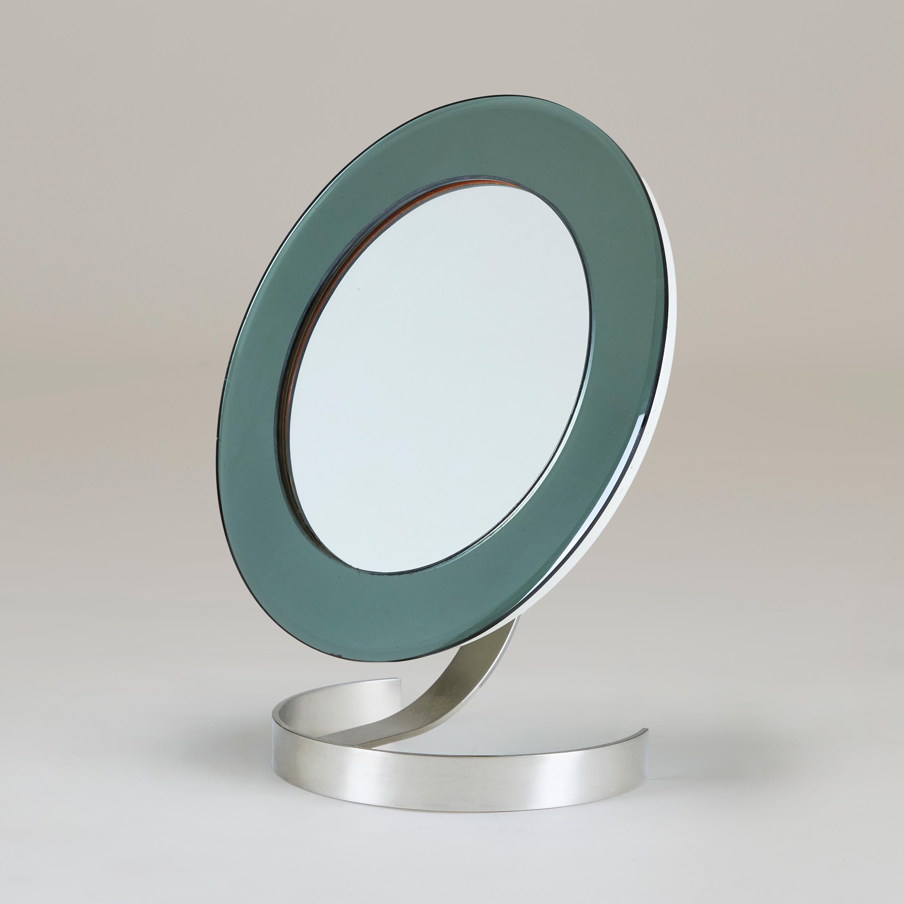 Outer wide smokey glass beveled mirror frame with inset silver mirror. Sits on polished nickel half circle base with curved back strut arm allowing the mirror to be adjustable. Space age mid-century design. Excellent quality and condition and very