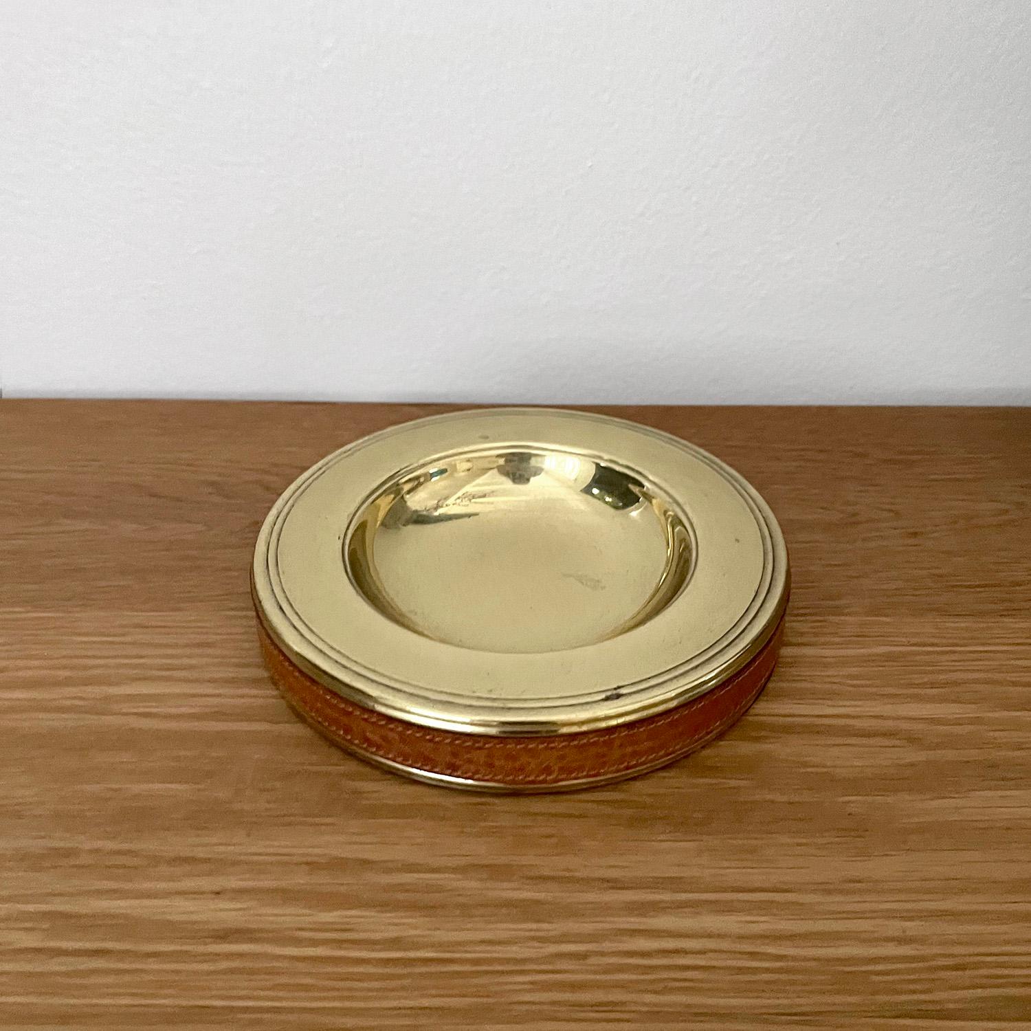 Italian aged brass & leather ashtray 
Italy, circa 1950s 
This handsome piece will be a great addition to any surface
Saddle leather band encompasses the aged brass ashtray
Light surface markings 
Patina from age and use 
This listing is for a