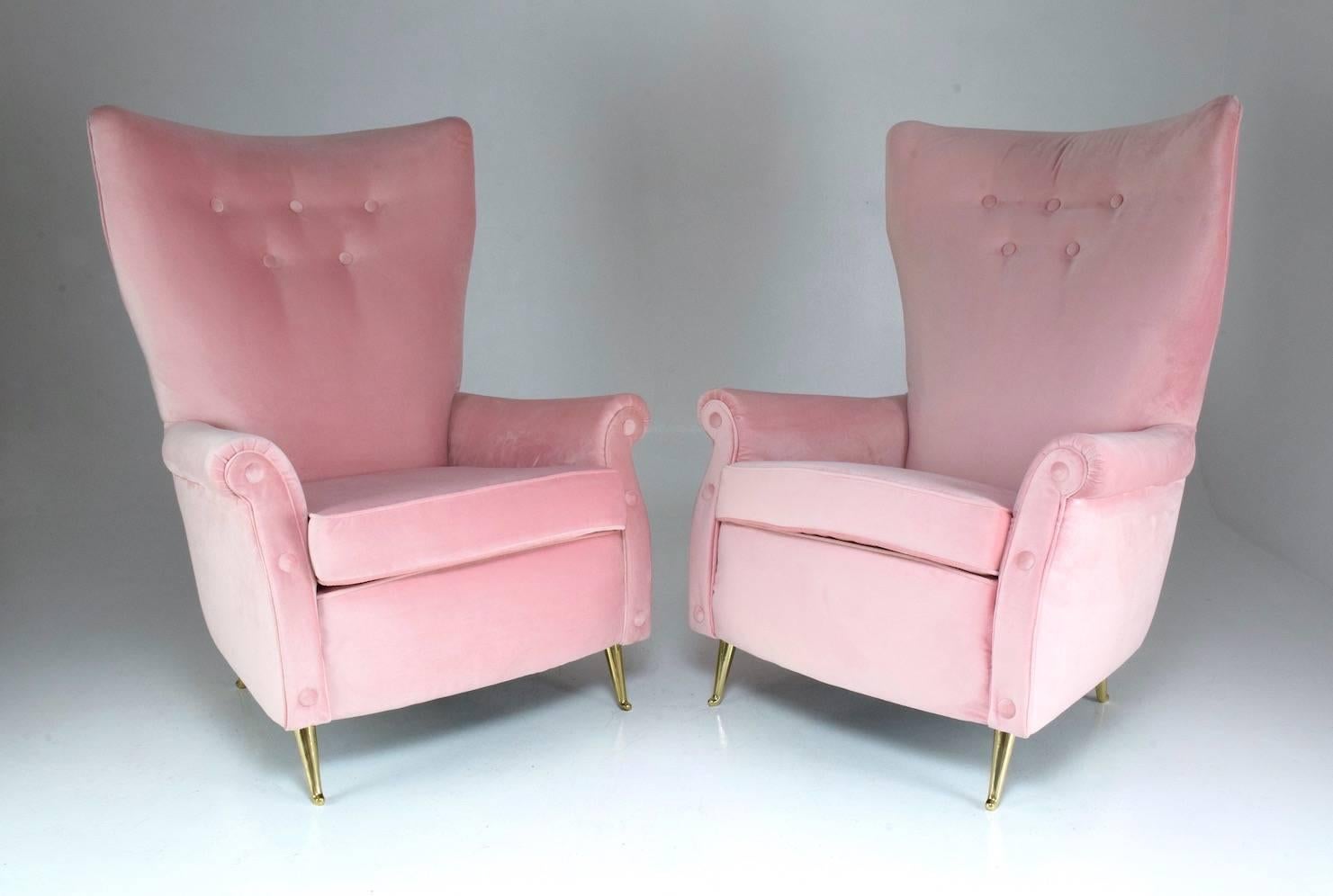 Pair of 20th century vintage Italian club armchairs designed with a high comfortable backrests and buttons manufactured by ISA Bergamo.
In fully restored condition with new foam padding, soft light pink velvet upholstery and iconic polished brass
