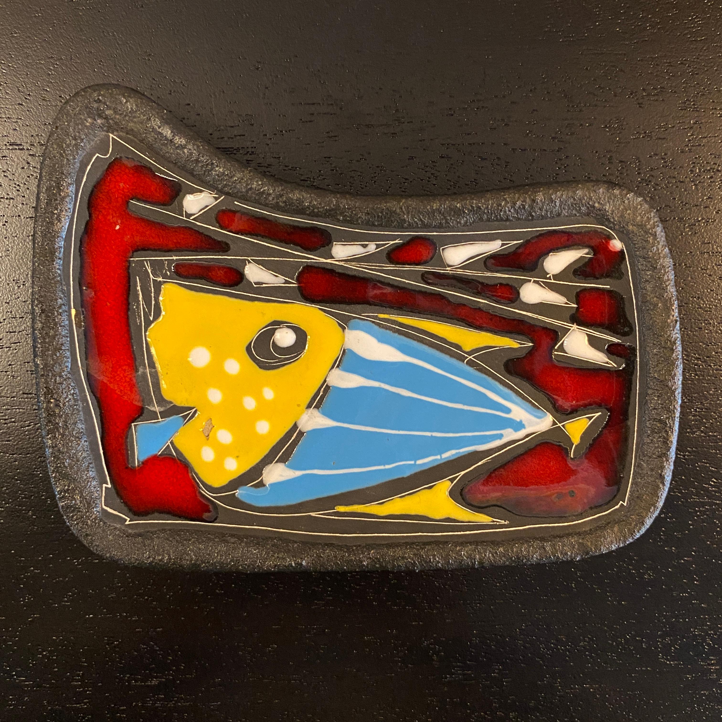 Italian, mid-century modern, art pottery, pin tray features a high glaze, abstract fish design in vibrant yellow, blue, and red hand painted on to the rough textured, charcoal colored surface for a wonderful contrast. Perfect as a pin tray, ring