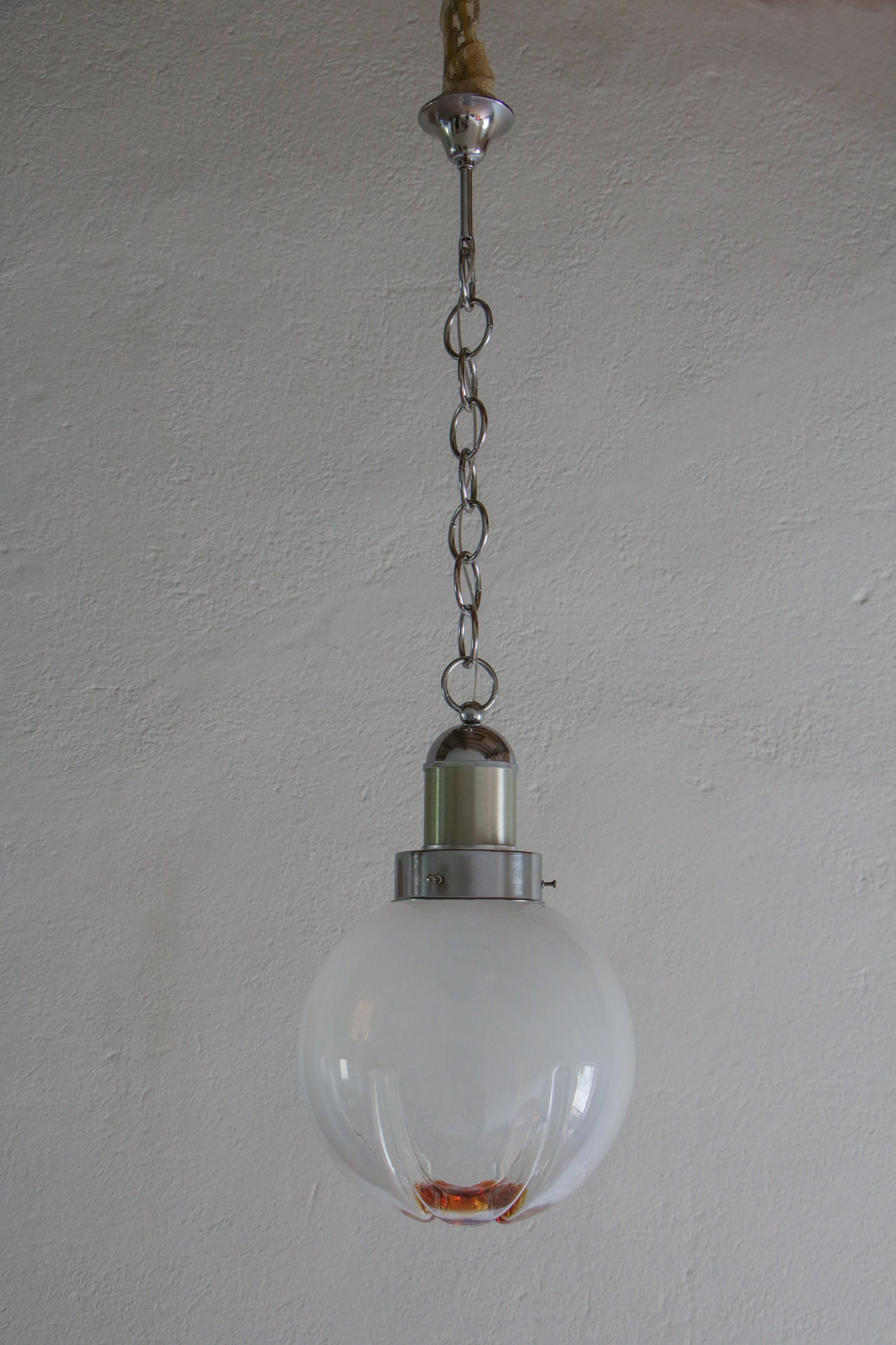 Italian space-age ball pendant lamp in smoked glass with a touch of orange, attributed to Mezzega, from the 1970s.
The structure and the pendant chain are in chromium steel. The blown smoked glass, apparently, is divided into six parts. A