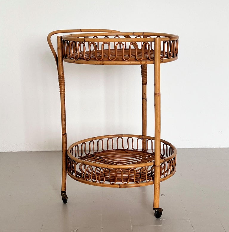 Gorgeous bar cart or trolley made of curved bamboo and rattan during the Italian mid-century in the 1960s.
The cart is circular with two tiers, handle, and 4 rollers. 
The four rollers are rolling smoothly.
Beautiful original and very good