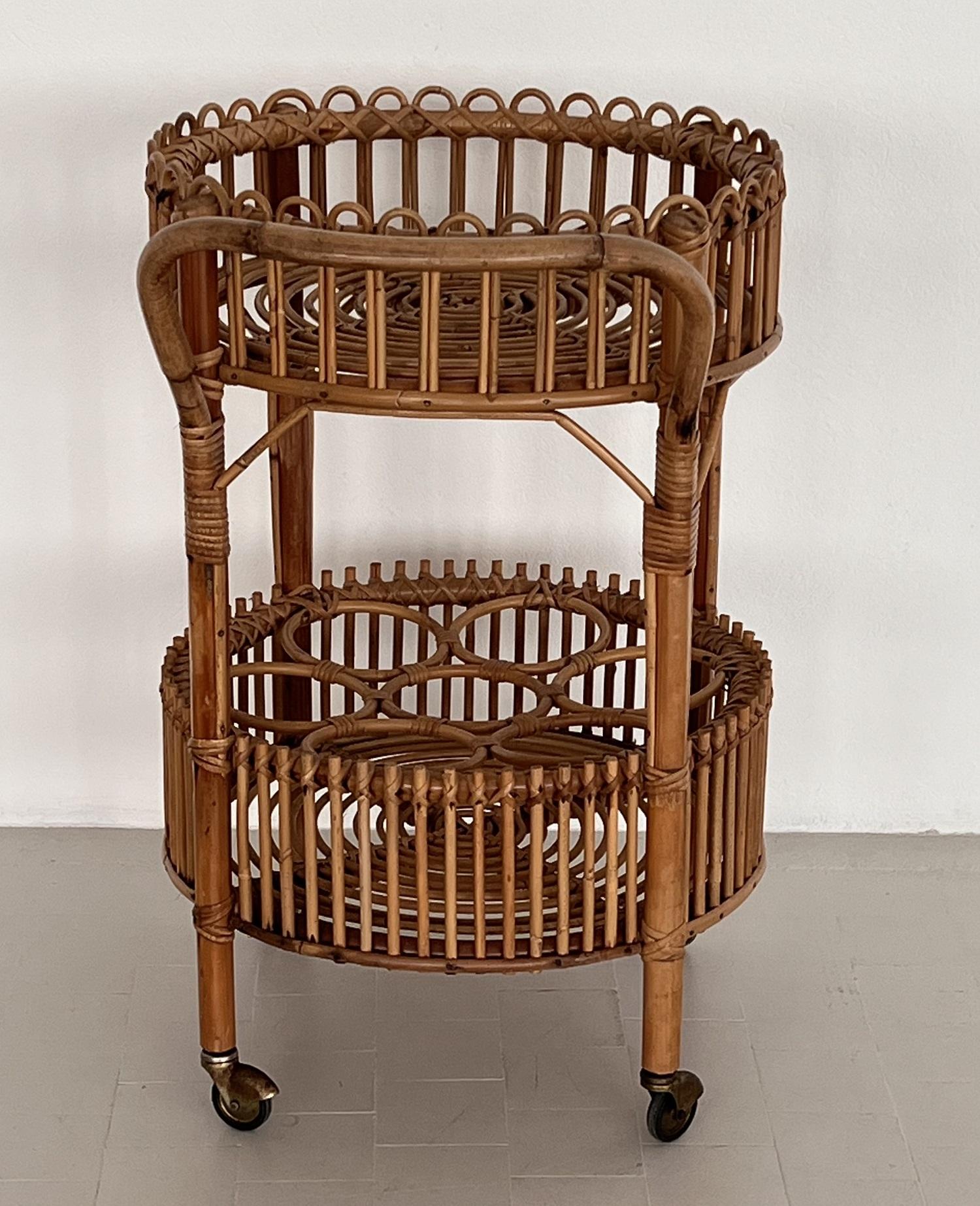 Gorgeous bar cart or trolley made of curved bamboo and rattan during the Italian mid-century in the 1960s.
The cart is circular with two tiers, handle, and rings on lower shelf to hold up to 7 bottles. 
The four rollers are rolling