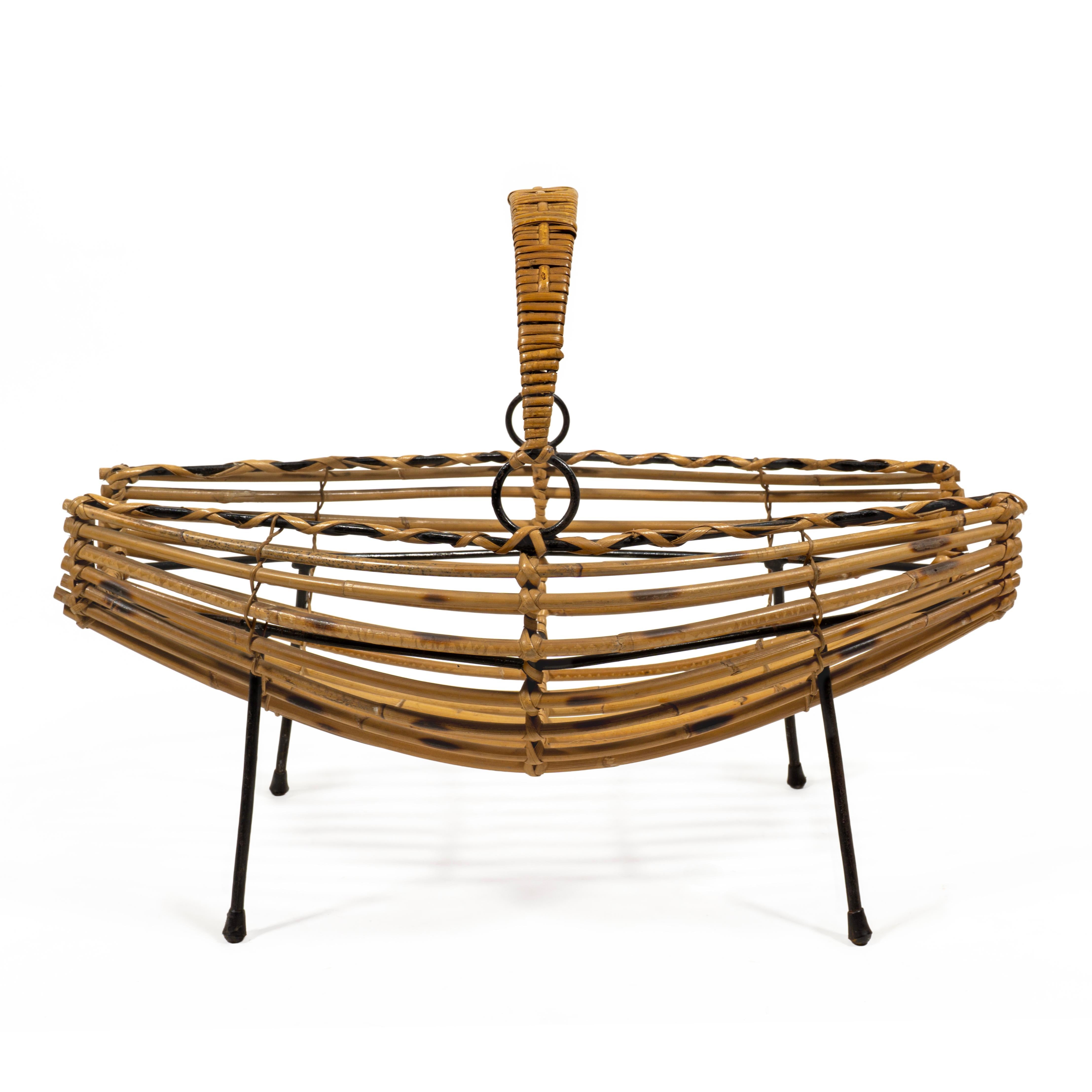 Affascinante portariviste italiano di metà secolo in bambù, rattan e ferro degli anni '60. Questo attraente portagiornali presenta una base smaltata nera in ferro piegato sostenuta dai suoi piedini originali in gomma. La base contiene un cesto curvo