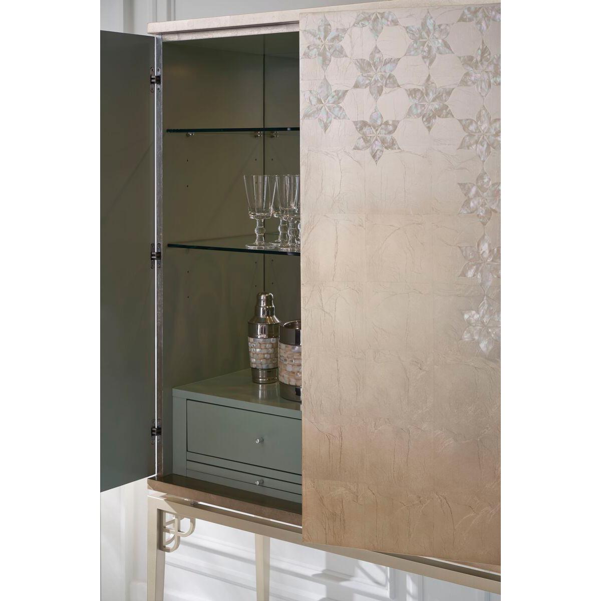 Its doors are detailed with Mother of Pearl accents and falling leaves, giving it a touch of luxury. The metal base is finished in a shade called 