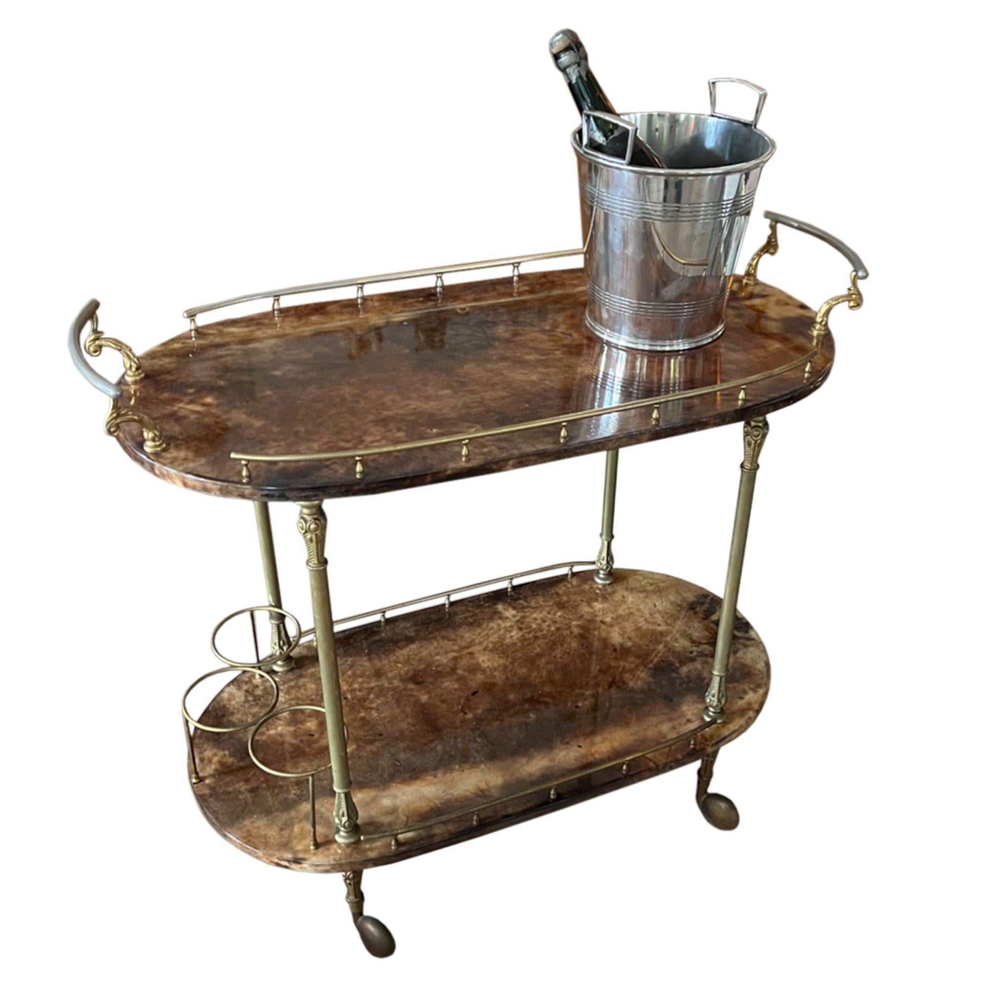 This wonderful lacquered goatskin and brass mid century drinks trolley was designed in Italy by Aldo Tura. His use of goatskin makes each piece unique. The gilt metal gallery, handles and bottle holders are slightly worn - as expected considering