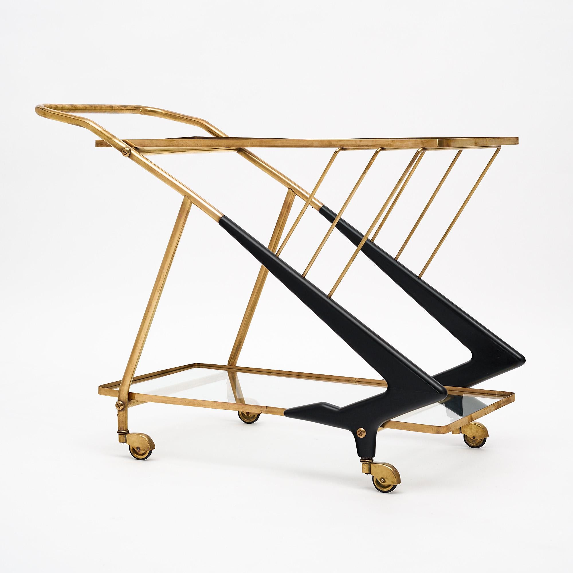 Bar cart, Italian, in a dynamic Mid-Century Modern style, by iconic designer Cesare Lacca. The ebonized wood and solid brass structure features two glass shelves and sits on four original casters.