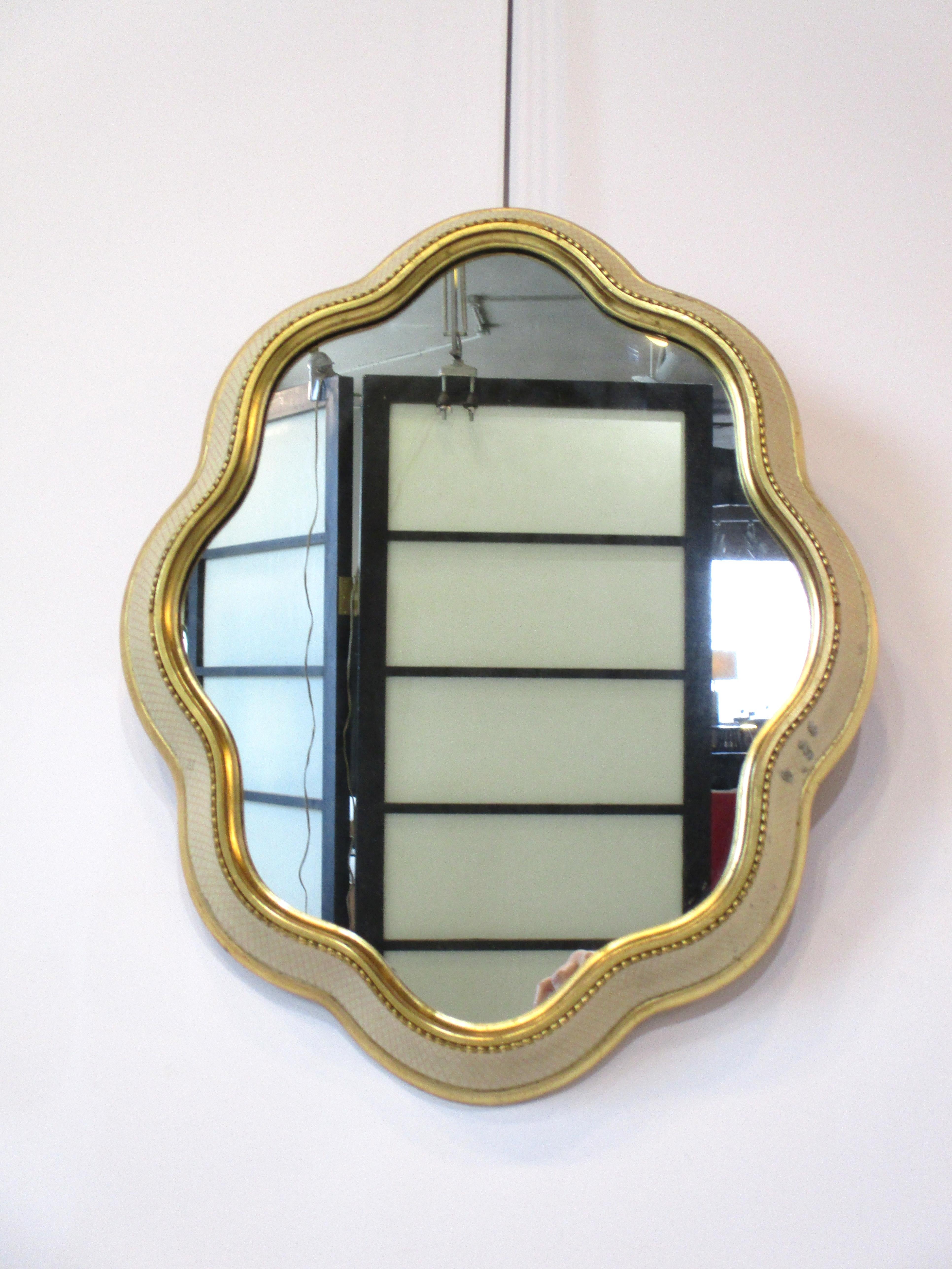 A very well crafted mid century sculptural biomorphic solid wood wall mirror with cream painted frame having hashed gold crisscross designs and gold wood beading line around the edge of the inner frame . Designed in the manner of Gio Ponti and the