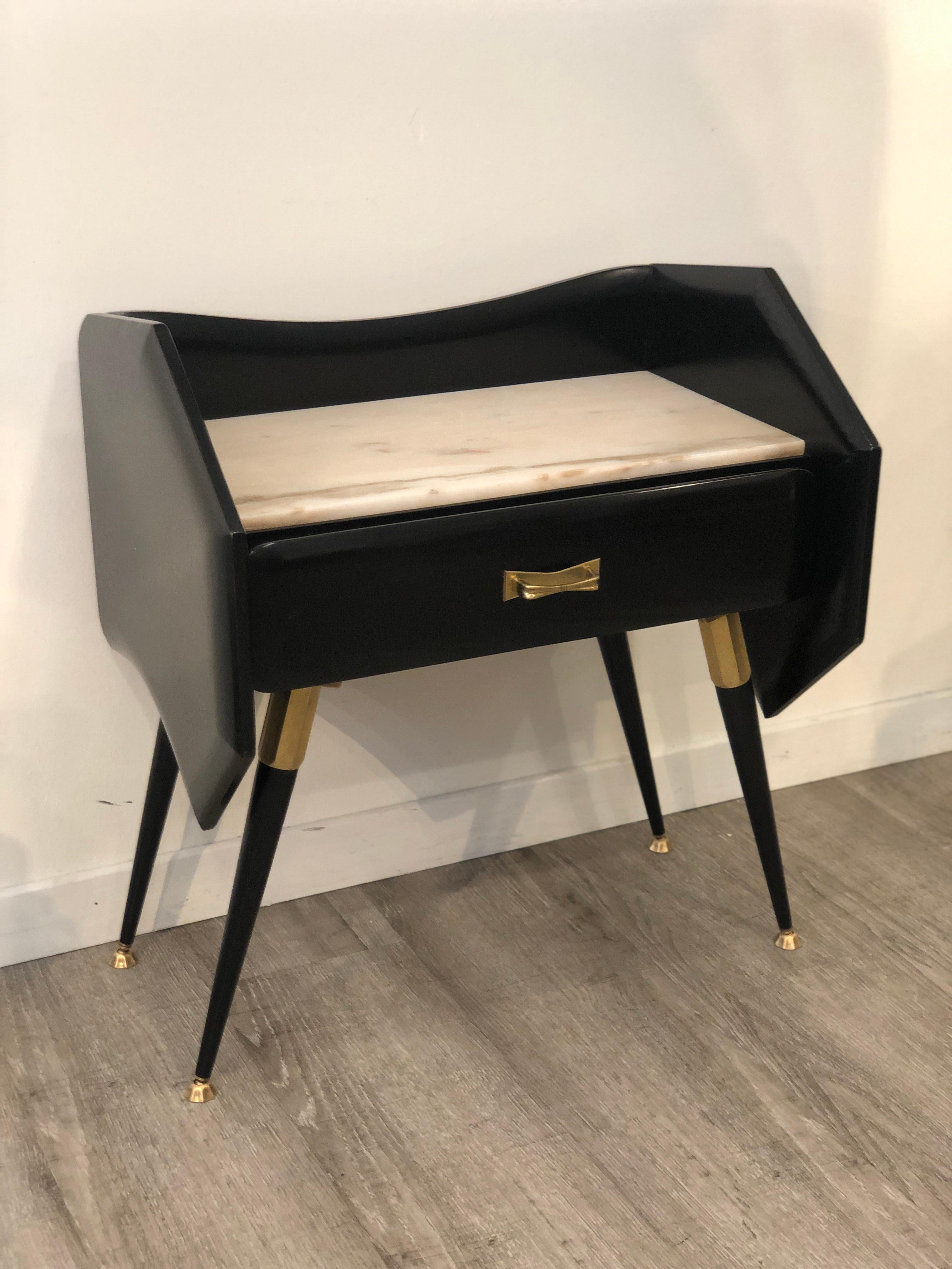 Black bedside tables with marble top and brass details and a drawer each. The brass is present on the legs and the handles. They feature the typical shape of mid-century 1950s Italian design. They have been restored in conservative way, fixing the