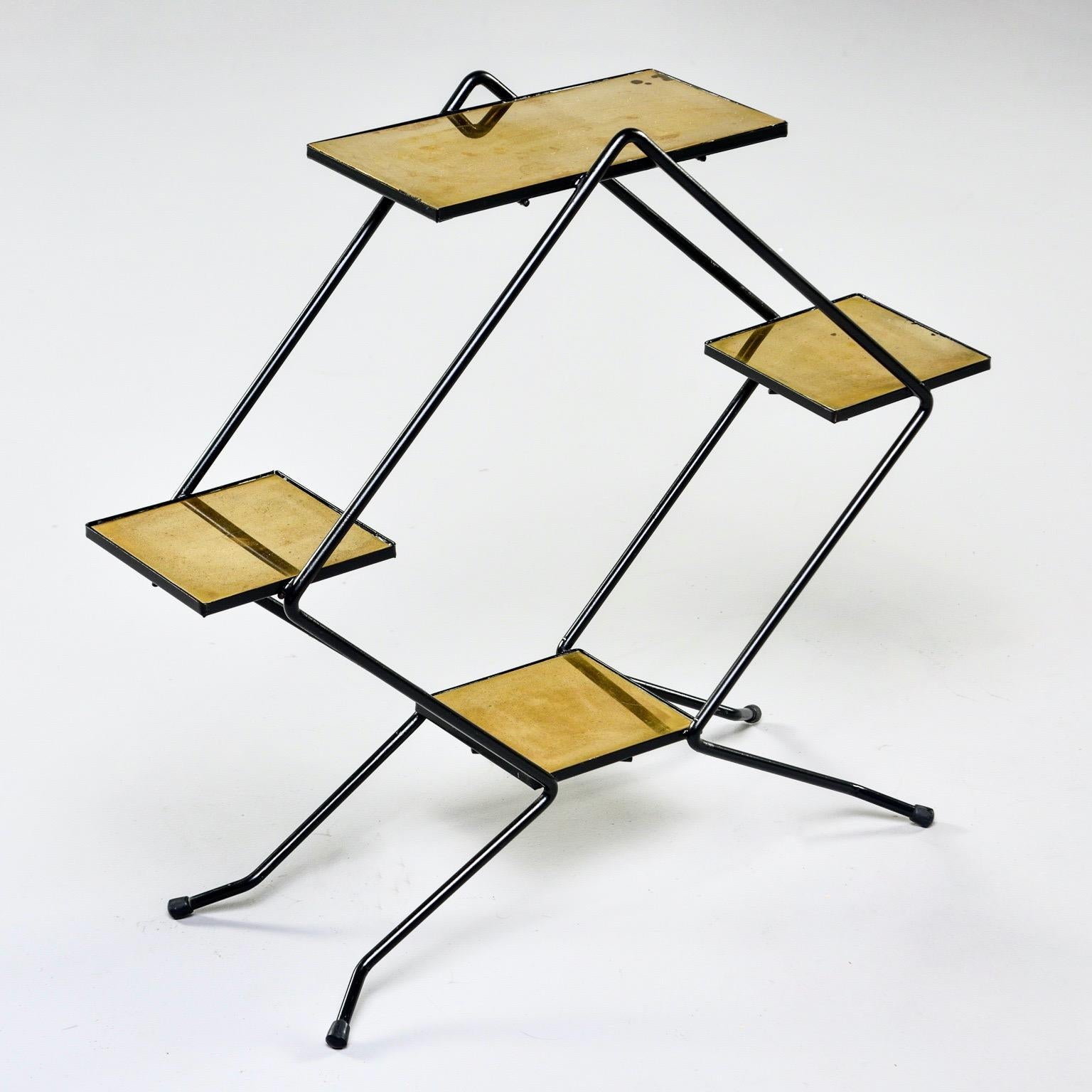 Italian display stand features a footed frame of slender black iron in an open diamond shape with four brass shelves, circa late 1950s-early 1960s. This can be used as a plant stand or on top of a larger table to display art and other objects.