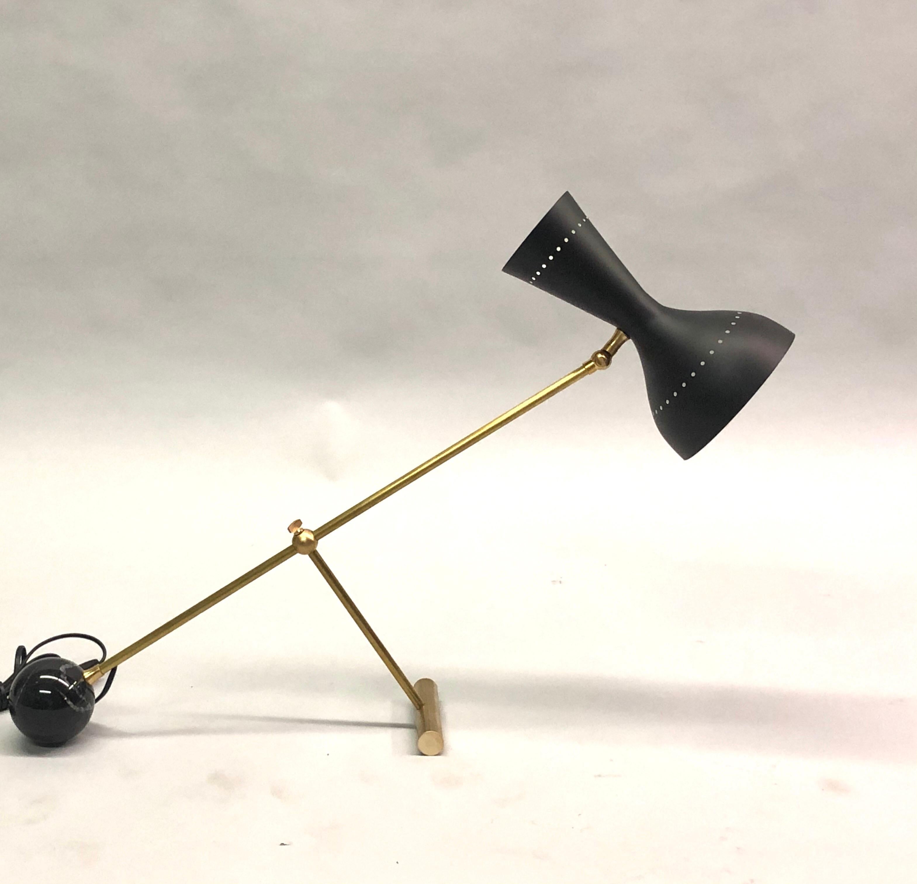 Elegant Italian Mid-Century Modern style desk or table lamp in the style of Angelo Lelli for Arredoluce composed of a round ball black marble base anchoring a solid brass articulating stem and a black enameled double shade with 1 socket in each