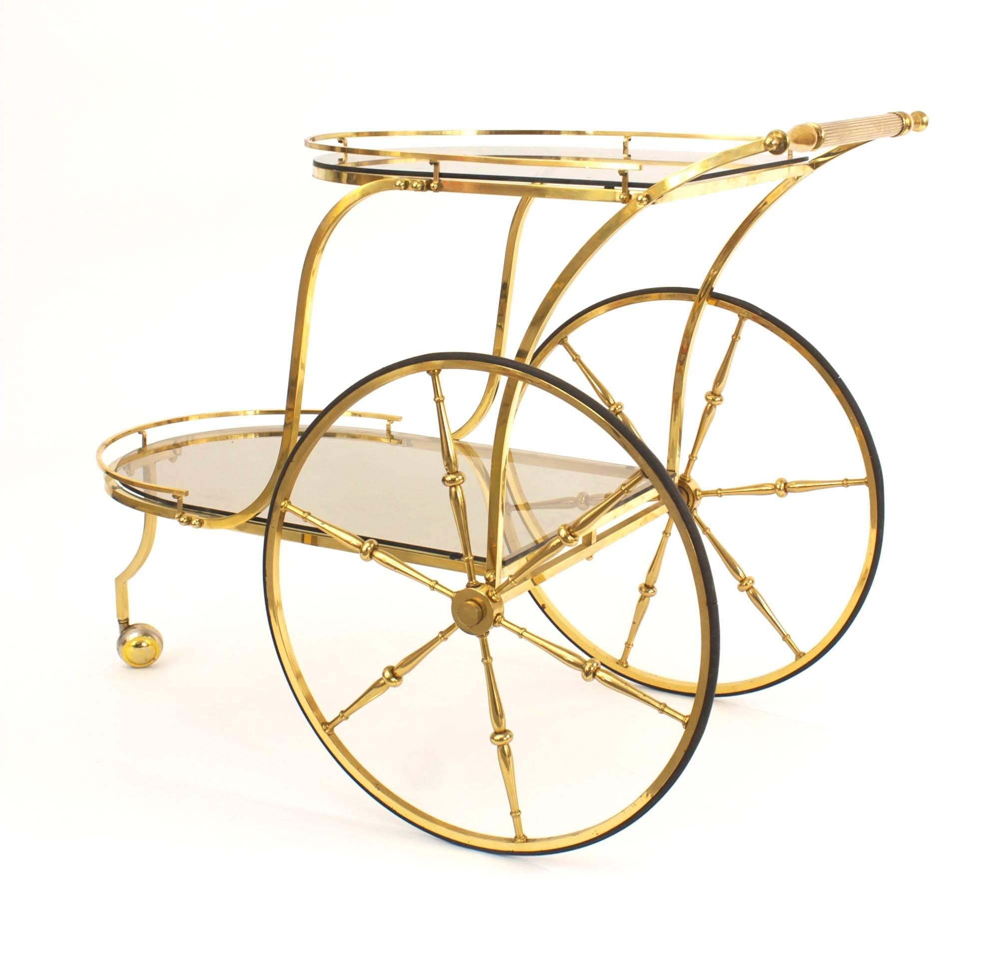 Italian Mid-Century (1950s) brass liquor/drinks trolley bar cart with one small front and two large back brass wheels and having a smoked glass top and shelf.