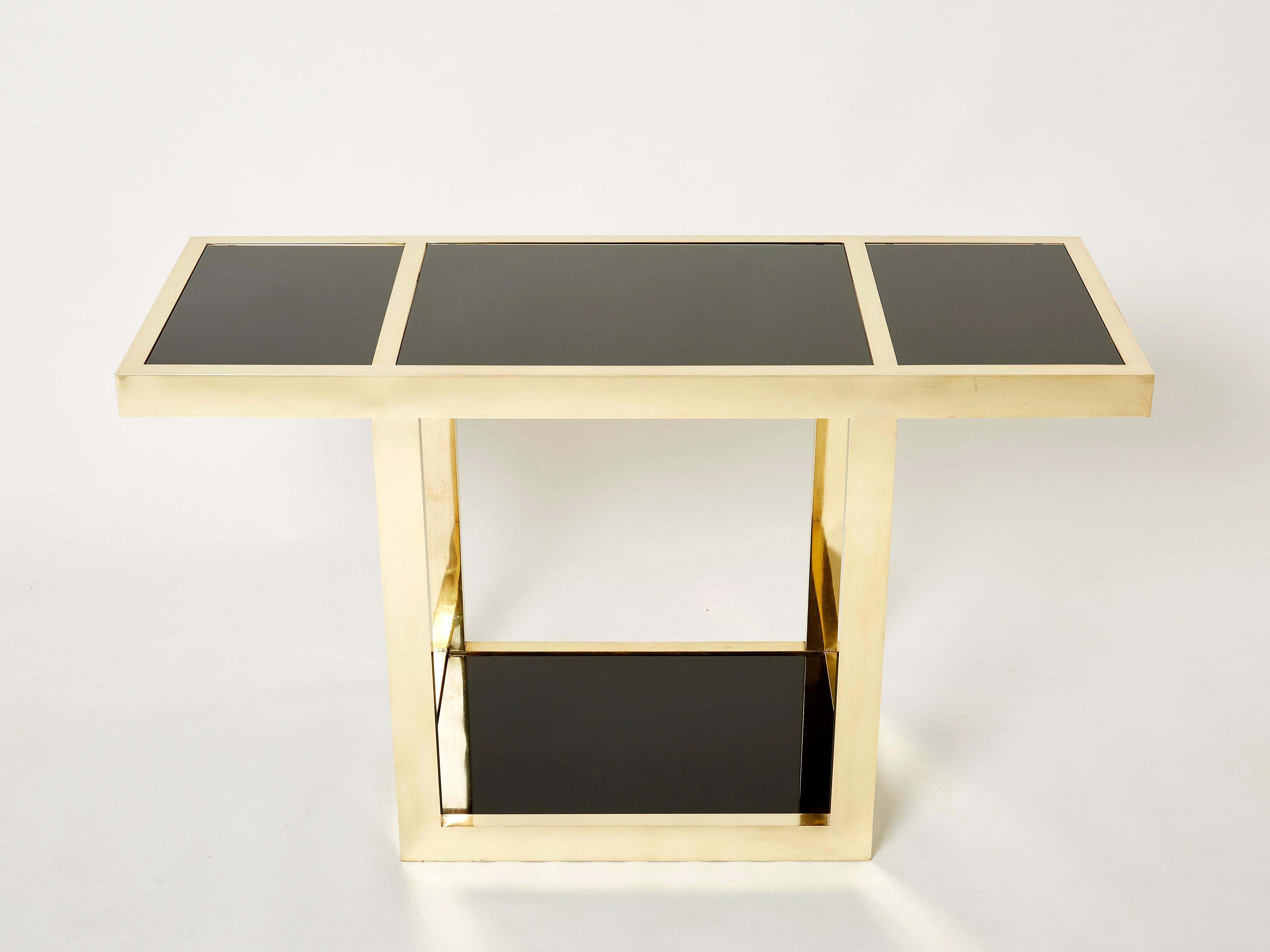 This beautiful thick brass and black opaline glass was made in Italy in the late 1970s. Symmetrical brass elements strike through black opaline glass tops, the result being an impressively sleek decorative piece. This console table deserves to be