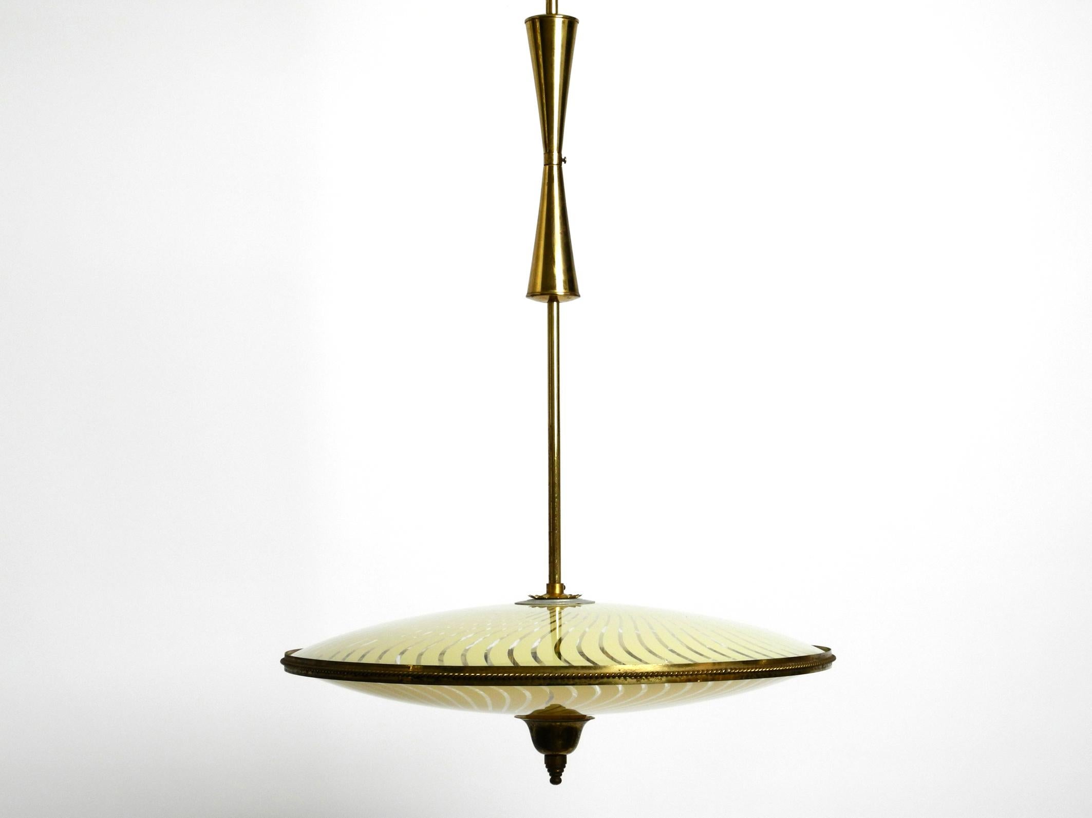 Beautiful Italian mid century brass ceiling lamp with an elegant double glass shade.
Great rare Italian design of the 1950's.
Frame, rod and canopy are made entirely of brass.
The identical shades above and below are made of glass with yellow