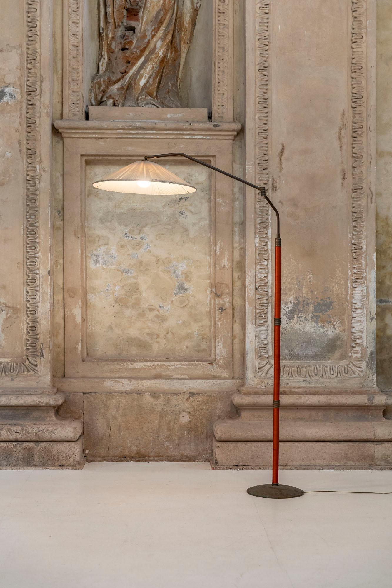 Mid-century brass floor lamp 
The lamp consists of a brass base that support a brass rod that is adjustable in height and in the length. 
The original lampshade is made in pleated fabric, beautiful orange silk wires along the structure.