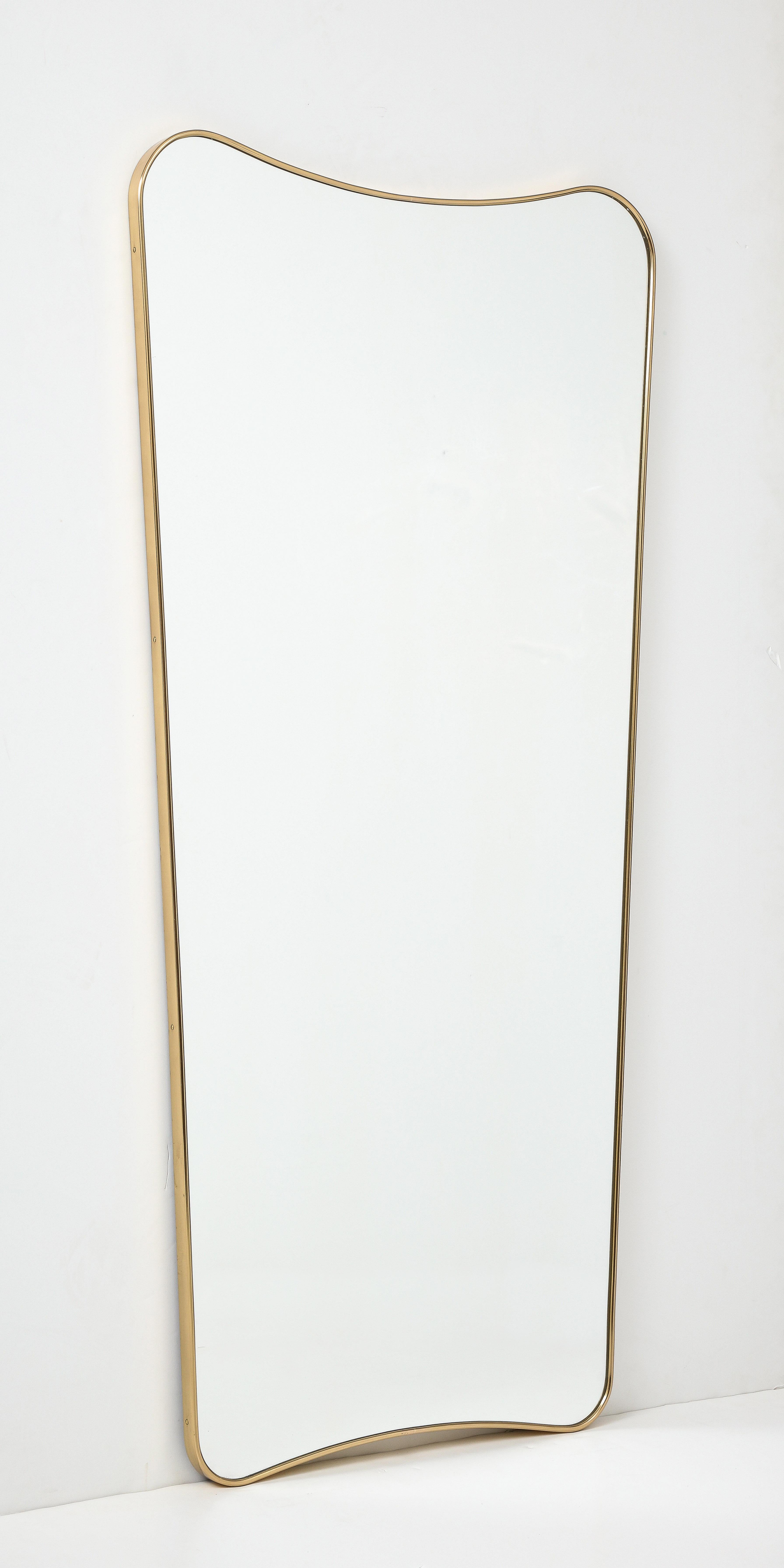 Midcentury modernist Italian mirror featuring a sinuous aged brass frame, styled after Gio Ponti.