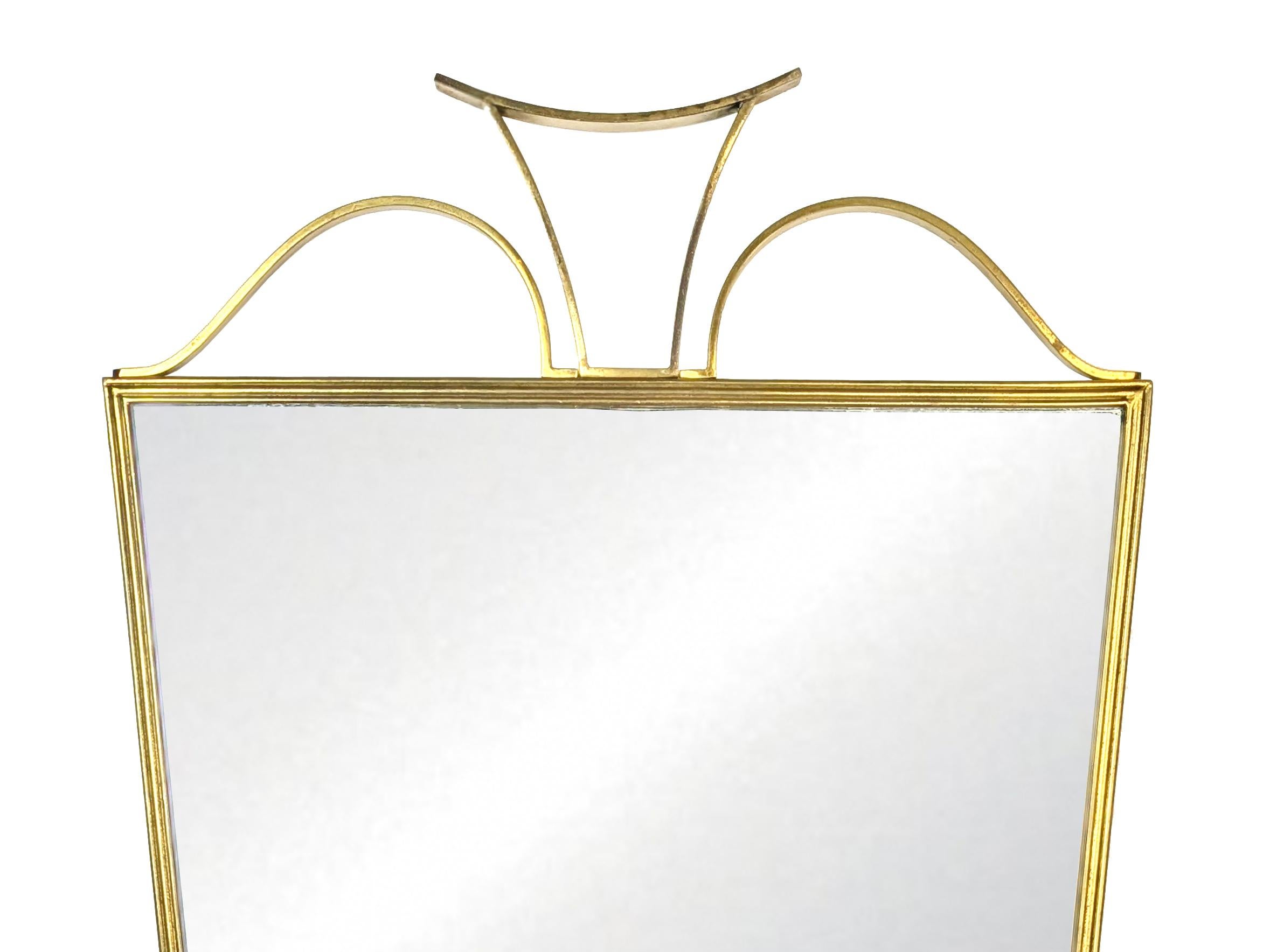 This wall mirror was designed in Italy in the 1950s. Brass and wood frame with stylized cymatium made up of 3 brass elements.
Very good vintage condition: Some oxidation spots on the mirror as showed in the pictures. Nice patina on the brass.